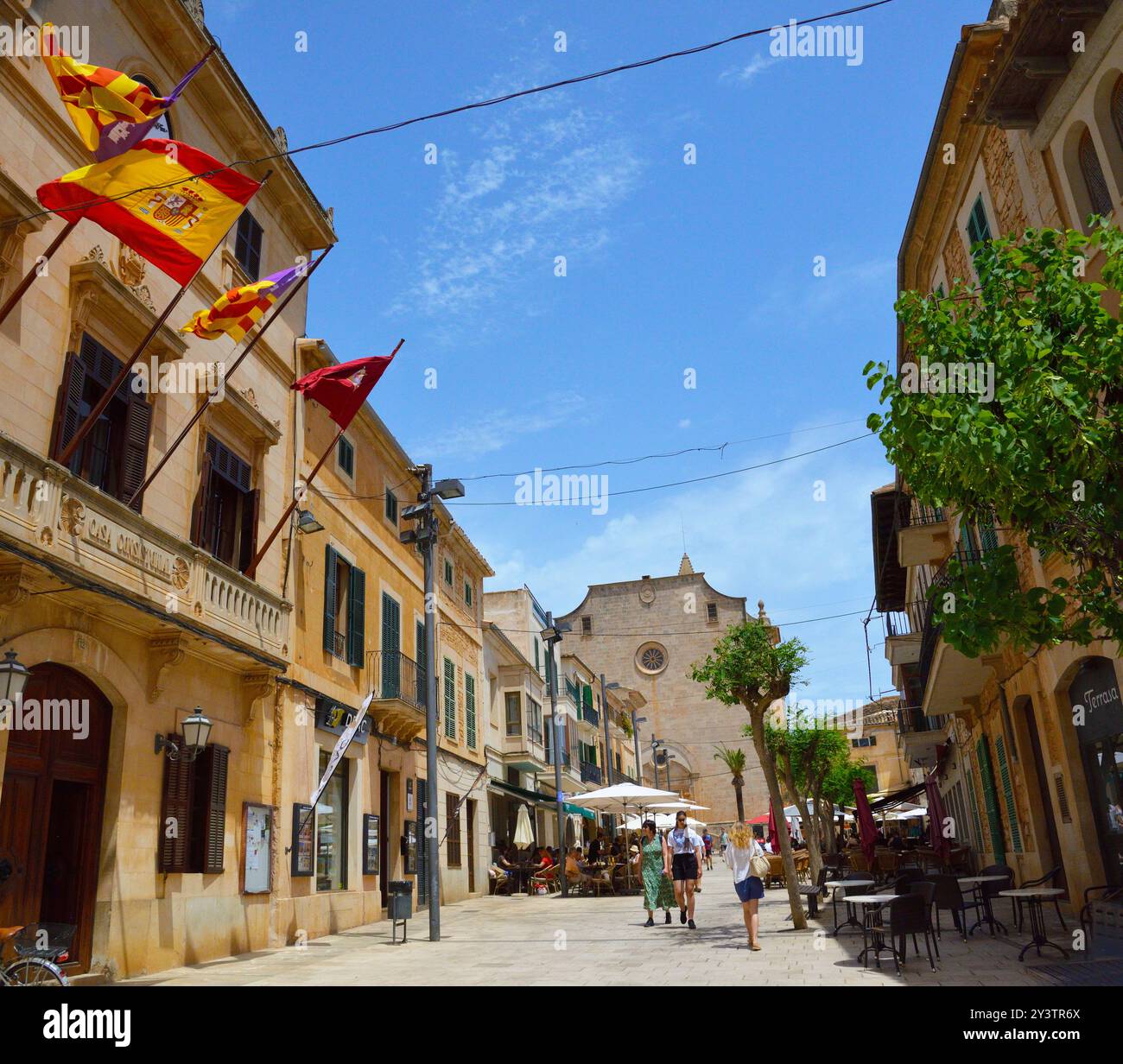 La città mercato di Santanyí guardando lungo Placa Major superava le bancarelle del mercato verso i ristoranti esterni e Sant Andreu de Santanyí in lontananza Foto Stock