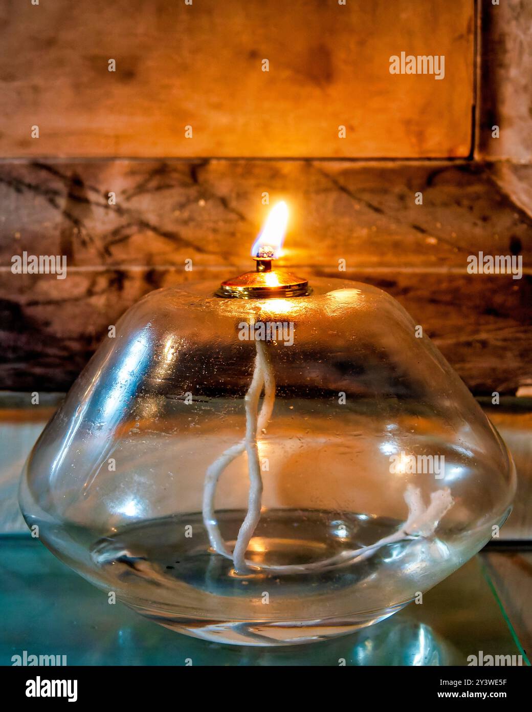 Una tradizionale lampada a olio di vetro che brucia in una chiesa, è usata per illuminare e simboleggiare la preghiera e la devozione. Foto Stock