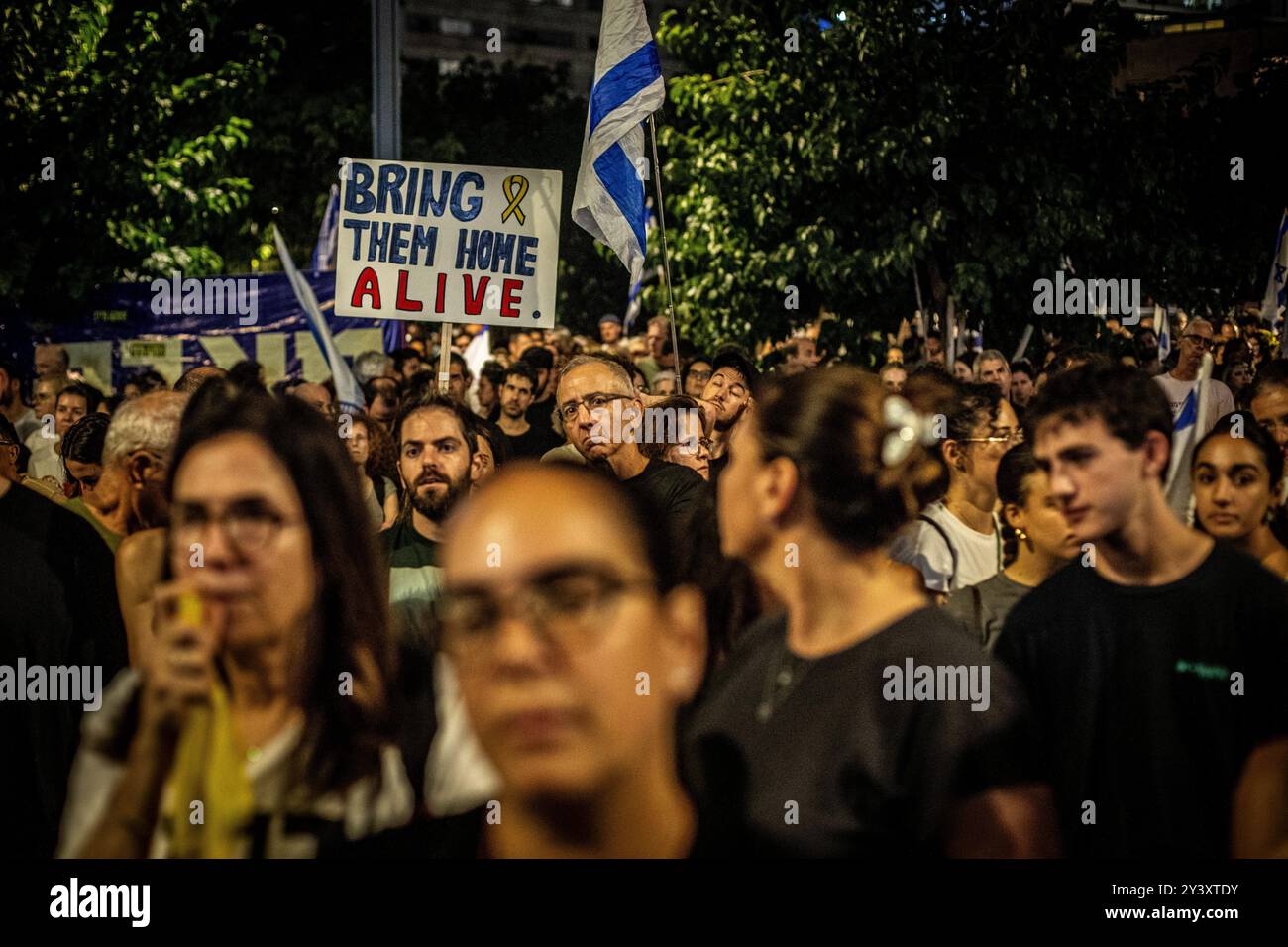 Tel Aviv, Israele. 14 settembre 2024. Manifestanti sotto un cartello che chiede il rilascio di tutti gli ostaggi, durante una manifestazione a Tel Aviv sabato 14 settembre 2024.decine di migliaia di persone si sono radunate a Tel Aviv e in Israele, chiedendo al primo ministro Benjamin Netanyahu e al suo governo di raggiungere un accordo per garantire il rilascio dei restanti ostaggi presi da Hamas durante gli attacchi del 7 ottobre. Crediti: Eyal Warshavsky/Alamy Live News Foto Stock