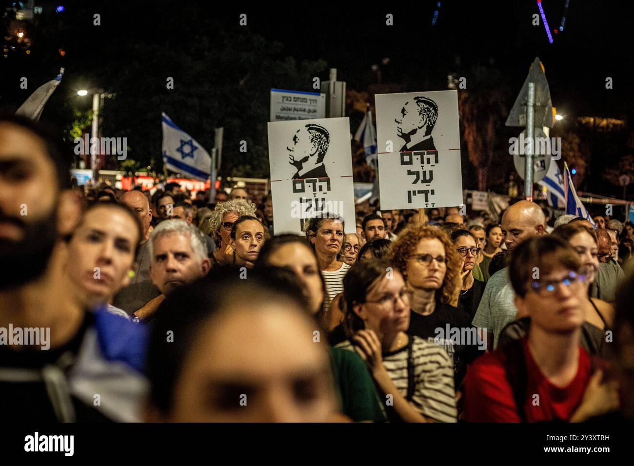 Tel Aviv, Israele. 14 settembre 2024. Manifestanti israeliani sotto un cartello che mostra il primo ministro israeliano Benjamin Netanyahu che recita in ebraico: "Il sangue sulle sue mani" durante una manifestazione a Tel Aviv sabato 14 settembre 2024.decine di migliaia di persone si sono radunate a Tel Aviv e in Israele, chiedendo al primo ministro Benjamin Netanyahu e al suo governo di raggiungere un accordo per garantire il rilascio dei restanti ostaggi presi da Hamas durante gli attacchi del 7 ottobre. Crediti: Eyal Warshavsky/Alamy Live News Foto Stock