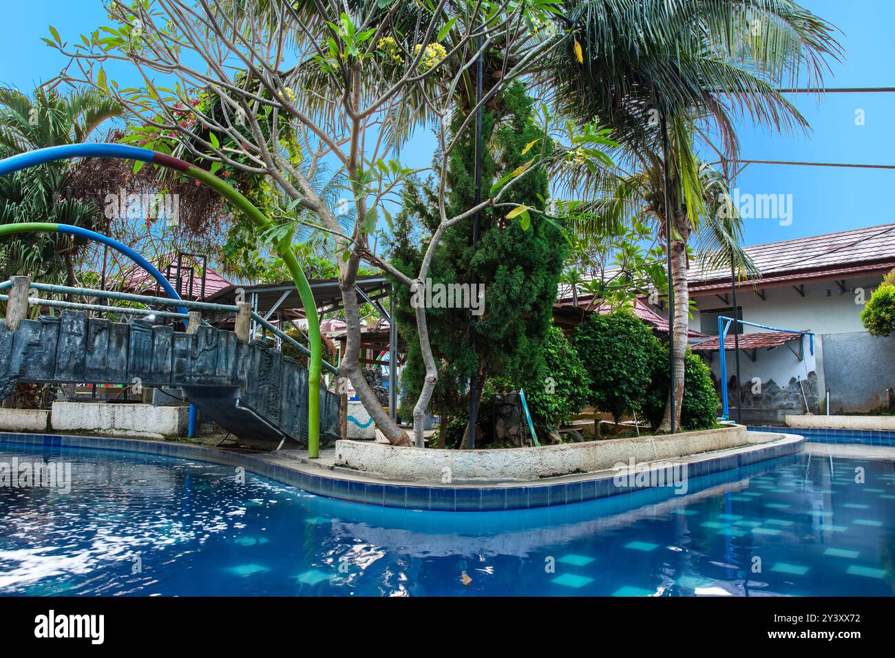 piscina con giardino e alberi accanto sotto il cielo azzurro. Parco acquatico con splendido giardino. Foto Stock