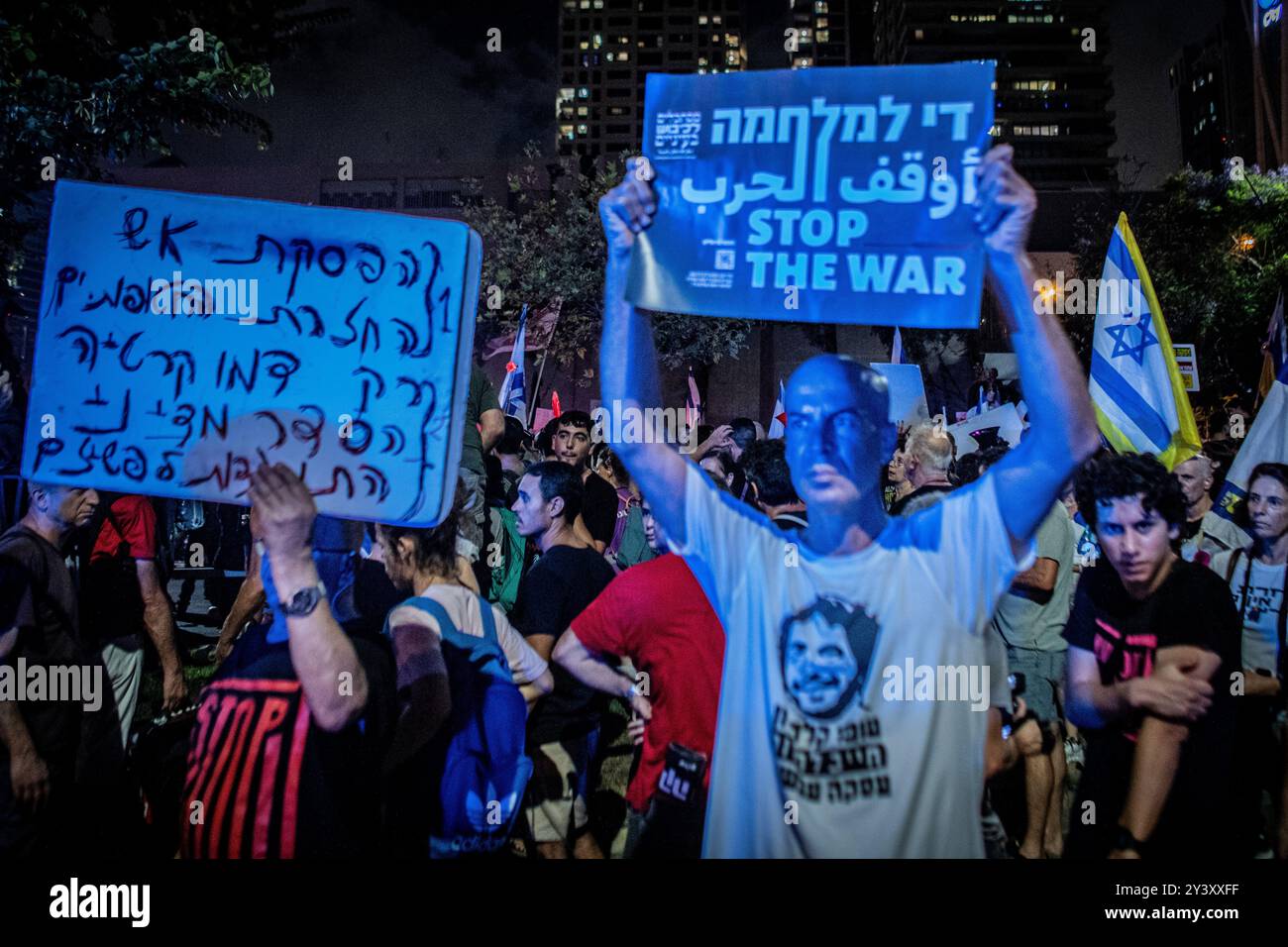 Tel Aviv, Israele. 14 settembre 2024. Un manifestante israeliano guarda come altri segnali ondeggianti che invitano a porre fine alla guerra, durante una manifestazione a Tel Aviv sabato 14 settembre 2024.decine di migliaia di persone si sono radunate a Tel Aviv e in Israele, chiedendo al primo ministro Benjamin Netanyahu e al suo governo di raggiungere un accordo per garantire il rilascio dei restanti ostaggi presi da Hamas durante gli attacchi del 7 ottobre. Crediti: Eyal Warshavsky/Alamy Live News Foto Stock
