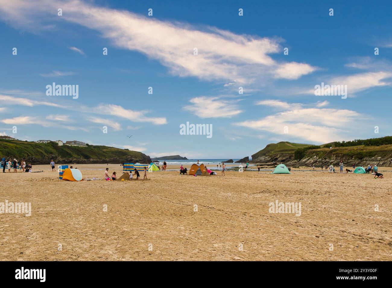 Una spiaggia soleggiata con gente che si diverte all'aria aperta. Le tende colorate sono allestite sulla spiaggia sabbiosa e le famiglie giocano e si rilassano. Il backgr Foto Stock