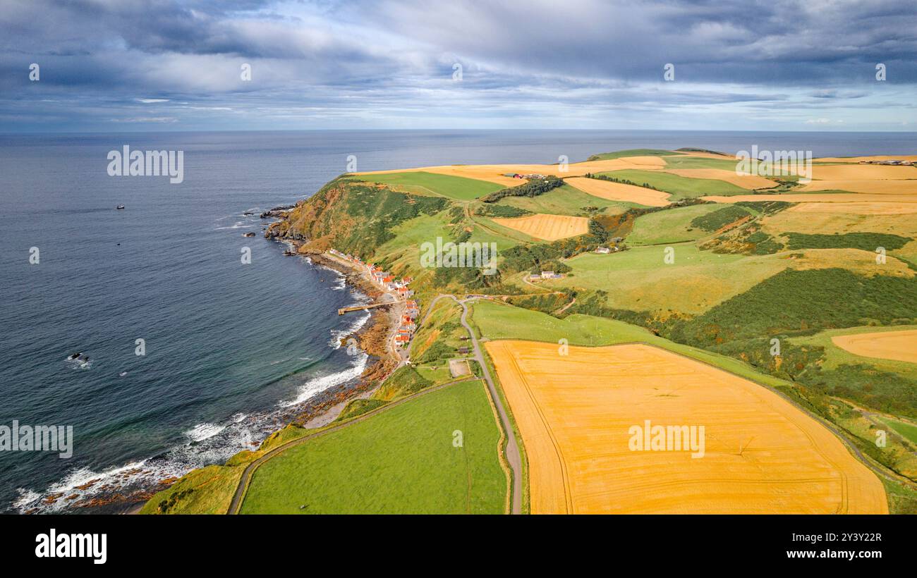 Crovie hamlet Aberdeenshire Scozia linea di case vicino al mare e mosaico di campi di orzo a fine estate Foto Stock