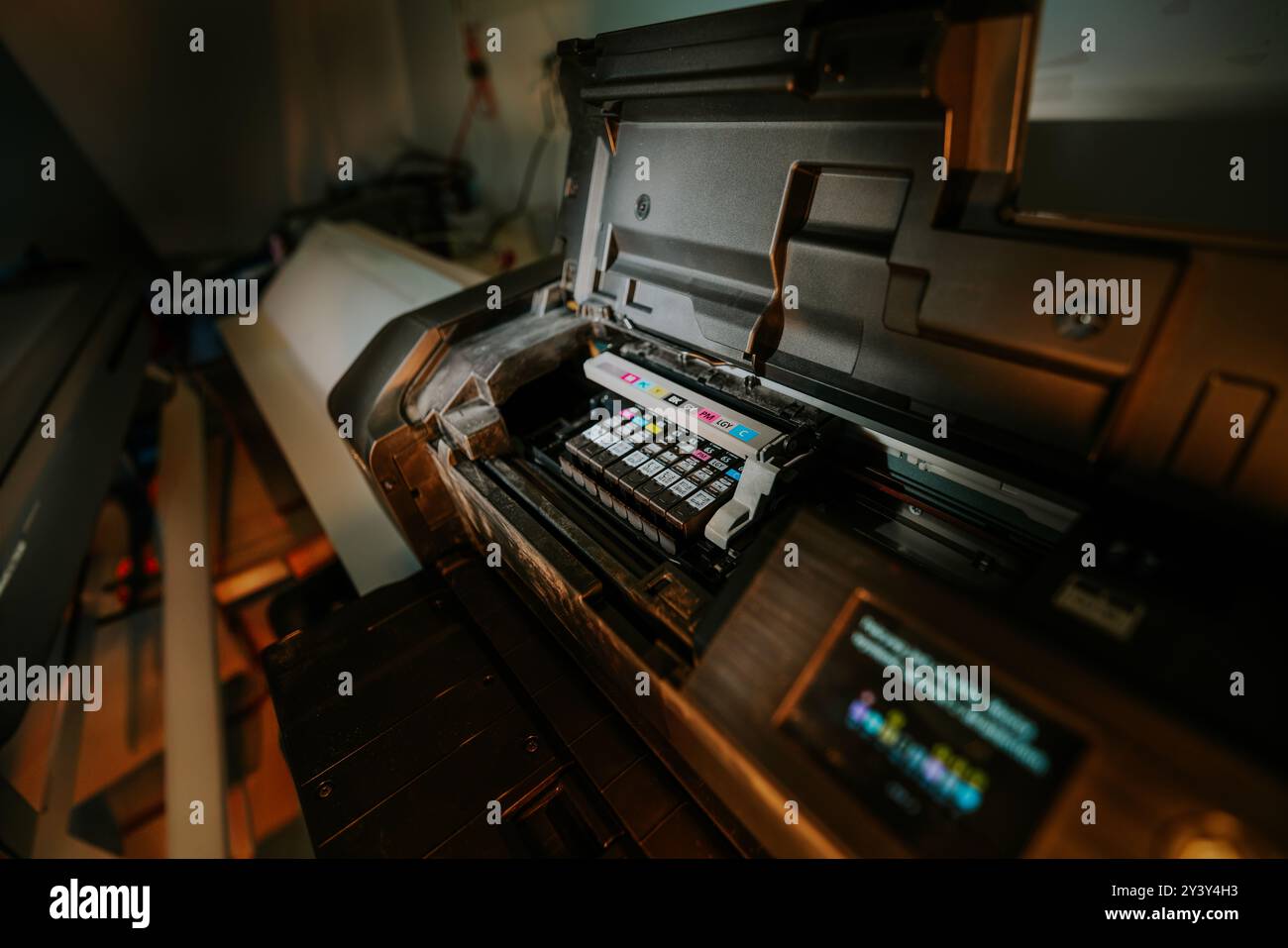 Stampante a getto d'inchiostro professionale. Cartucce di inchiostro. Studio di stampa. Sfondo scuro. Foto Stock