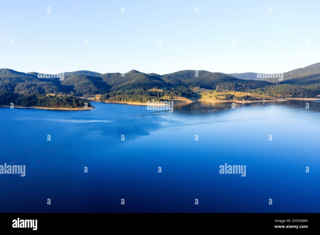 Lago e montagne circondati da foreste in Bulgaria. Allevamenti ittici di trote e altri pesci sul lago. Colpo aereo con un drone Foto Stock