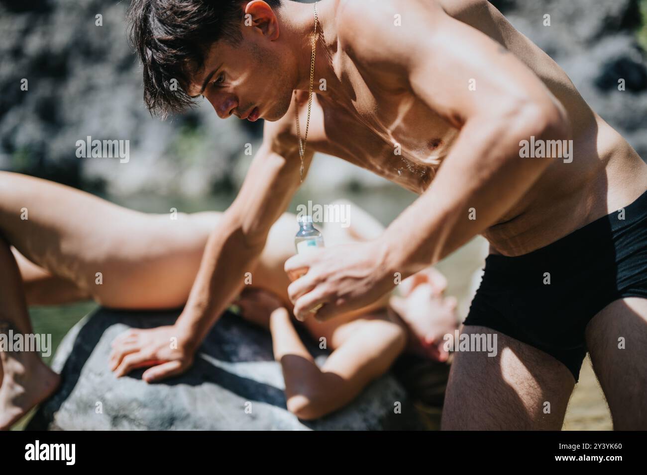 Giovane coppia che si gode una giornata estiva al fiume, applicando la crema solare l'uno all'altro Foto Stock