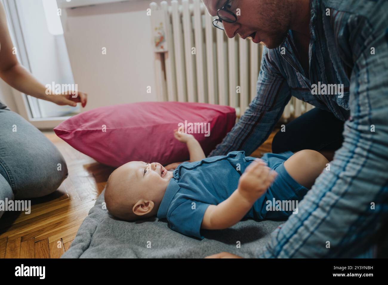 Padre che gioca con il bambino sul pavimento di casa con il cuscino rosa Foto Stock