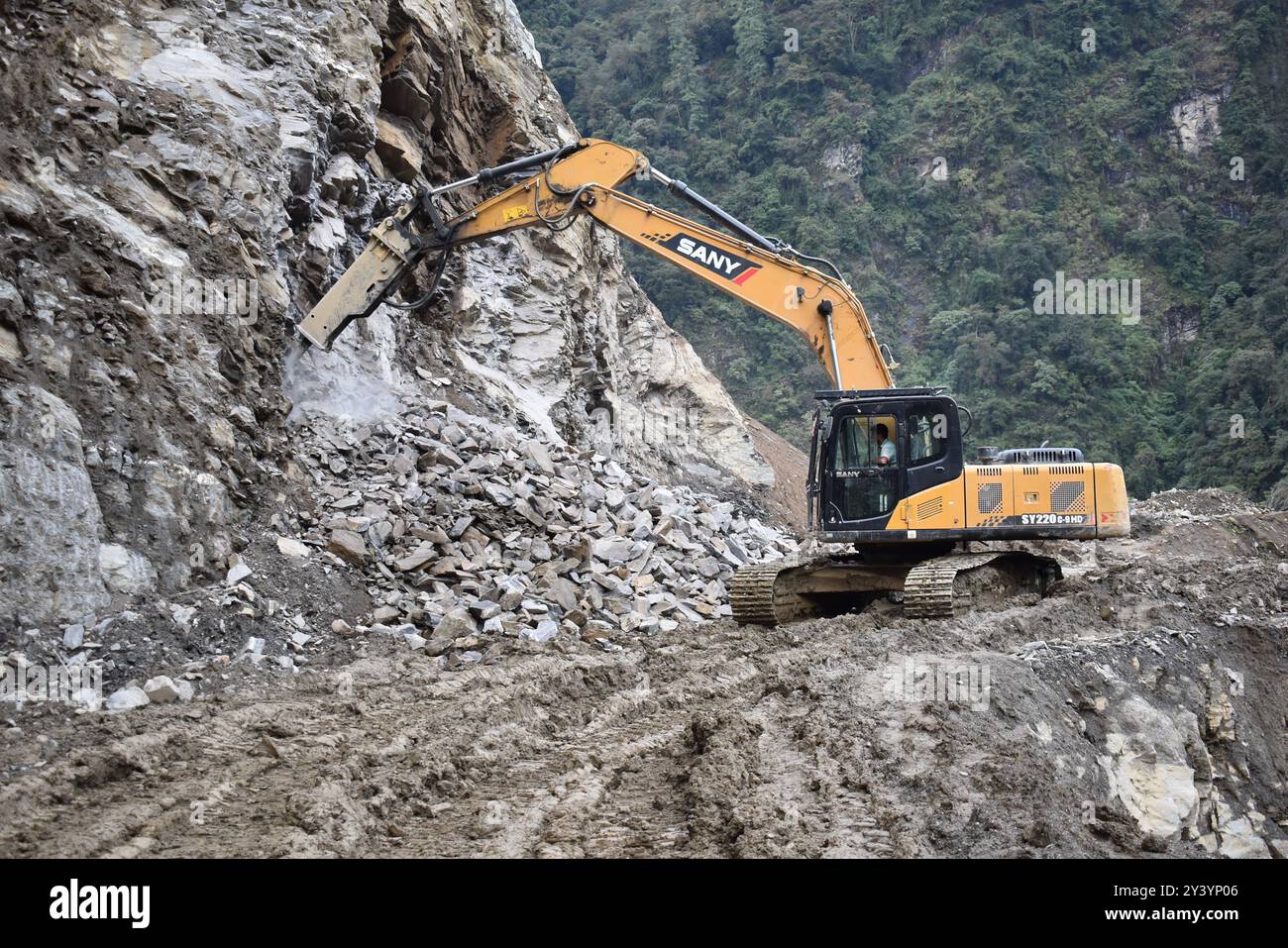 Il taglio e la rottura della roccia dura nei boschi da parte di un escavatore, situazioni molto difficili, luoghi pericolosi, la vita è a rischio Foto Stock