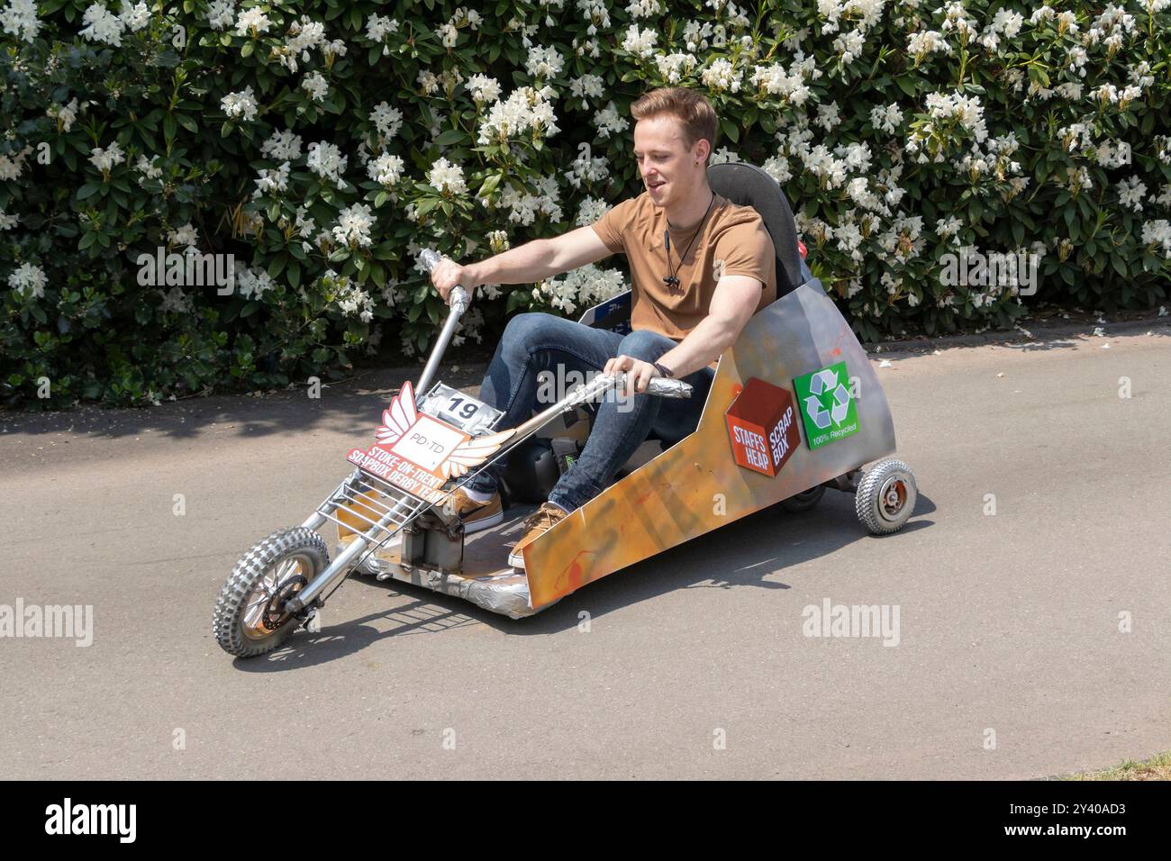Young Man in sella a un go-kart fatto in casa con simboli di riciclaggio in una divertente gara di karting a Stoke, a Trent staffordshire, Regno Unito Foto Stock