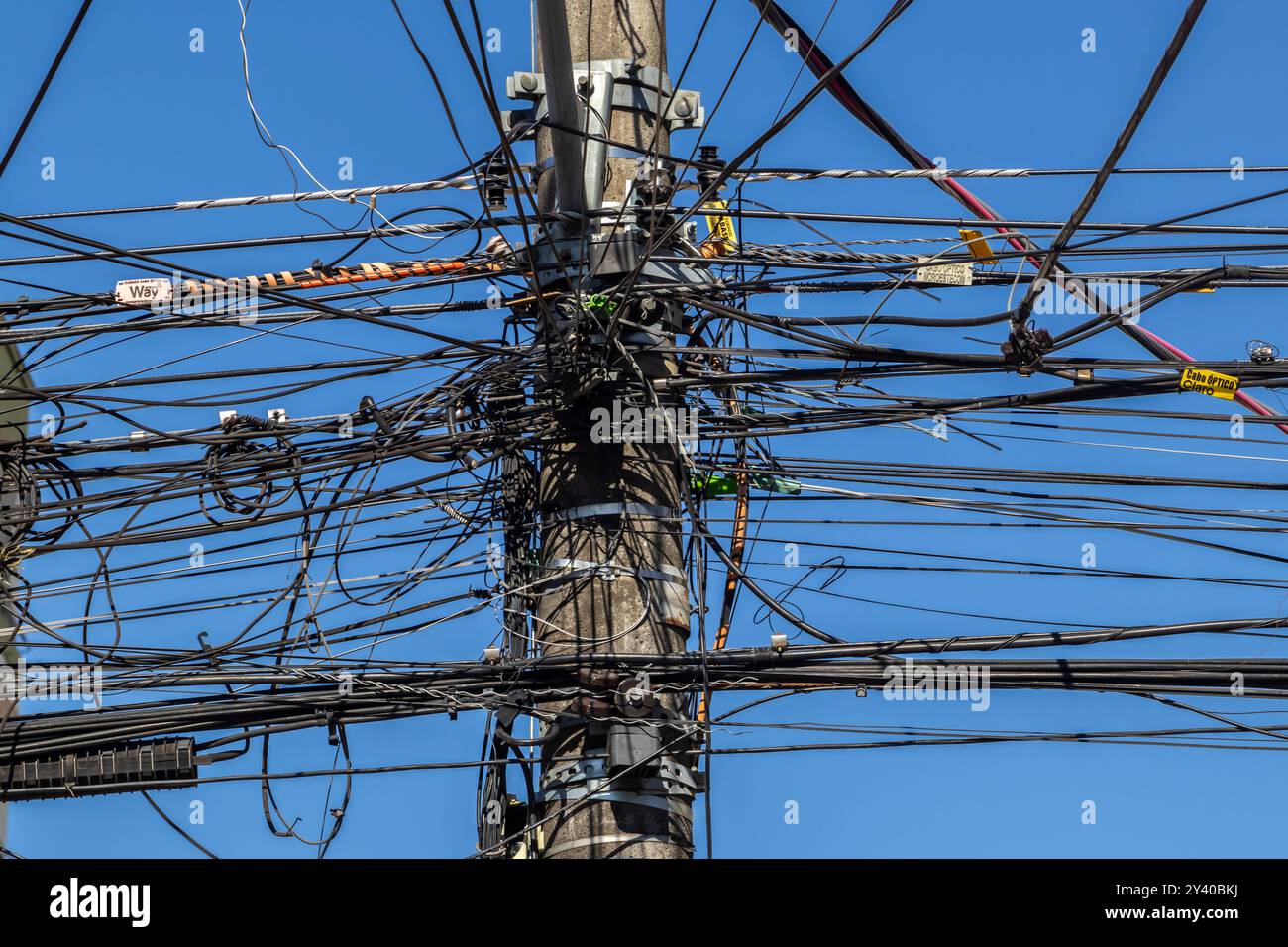 Marilia, SP, Brasile, 12 giugno 2024. Molti fili collegati al polo elettrico, il caos di cavi e fili su un palo elettrico, sfondo blu del cielo, Foto Stock