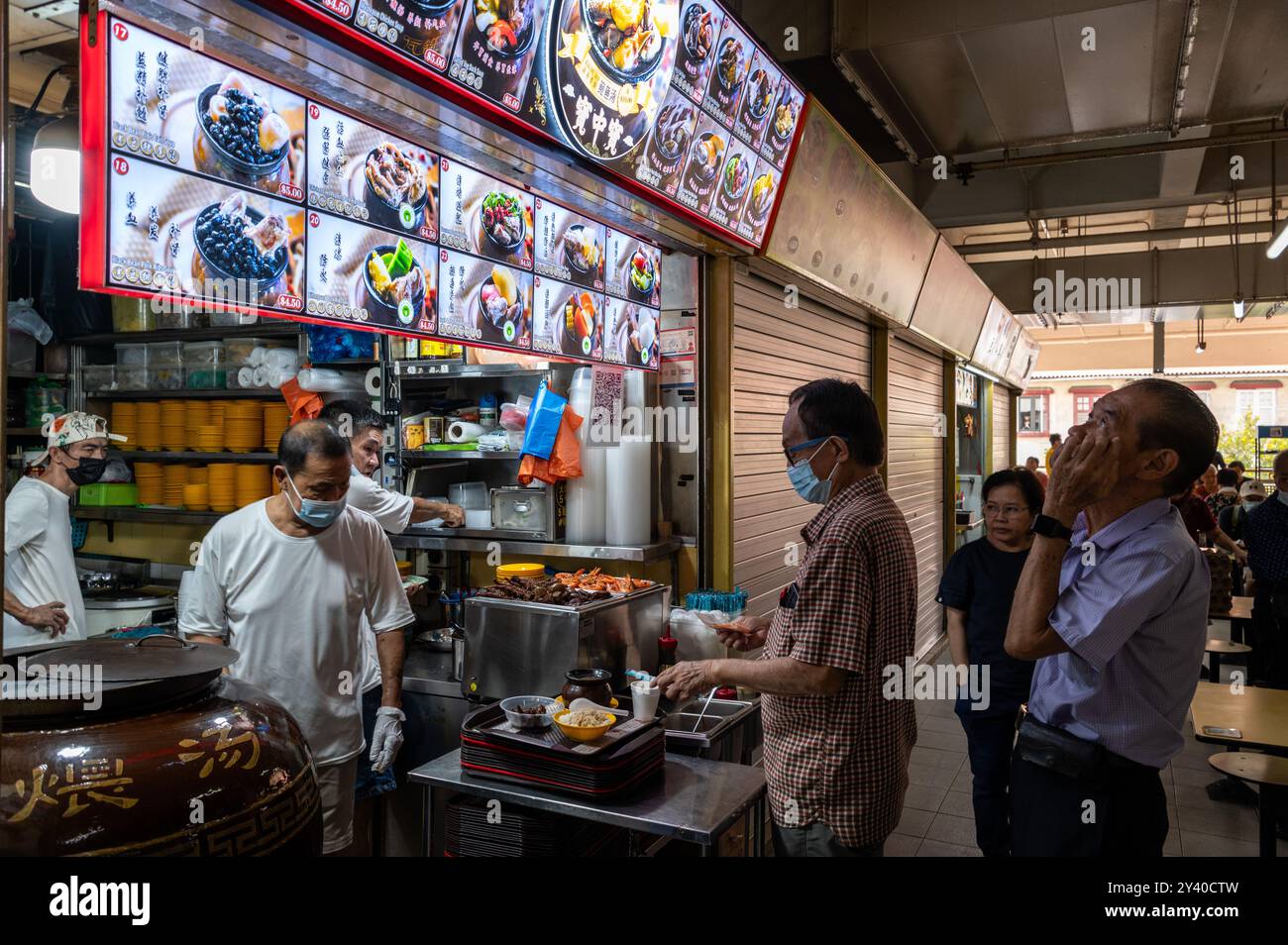 I clienti fanno la fila a turno per essere serviti in uno dei piccoli ristoranti che servono piatti tradizionali cinesi nel complesso Chinatown a Chinatown, un vecchio edificio storico Foto Stock