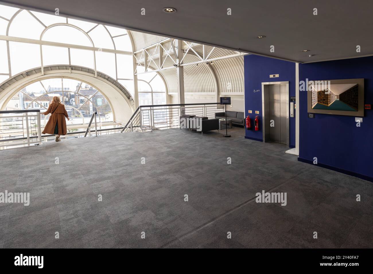 Donna incorniciata da luce e architettura; il movimento grazioso incontra il design elegante al Business Design Centre Foto Stock