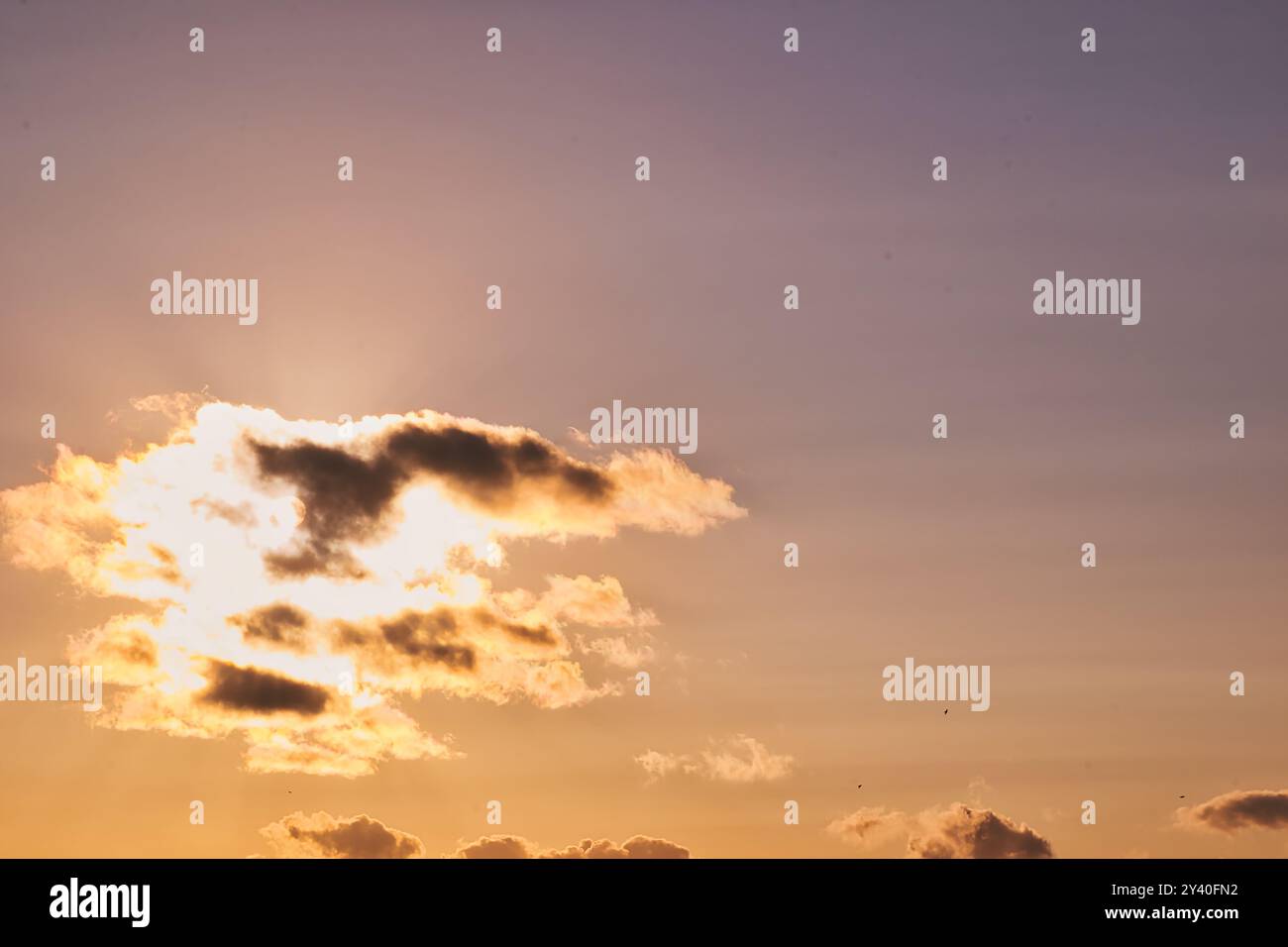 Un bellissimo tramonto con morbide nuvole illuminate dal sole, che creano un'atmosfera calda e serena. Il cielo passa dalle tonalità blu a quelle dorate, enhan Foto Stock