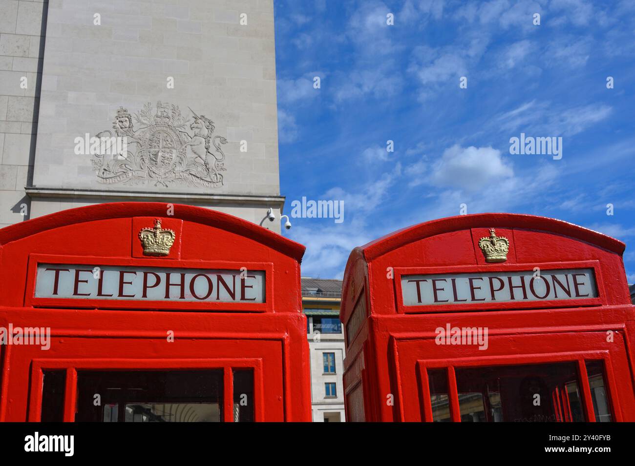 Londra, Regno Unito. Royal Opera House Arcade a Covent Garden. Royal Coat of Arms e cabine telefoniche rosse Foto Stock