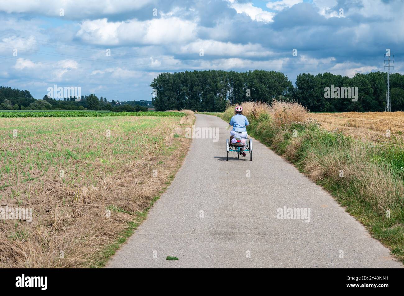 Ritratto di una donna di 41 anni con la sindrome di Down che guida il suo triciclo nei campi, Hakendover, Tienen, Belgio. Modello rilasciato Foto Stock