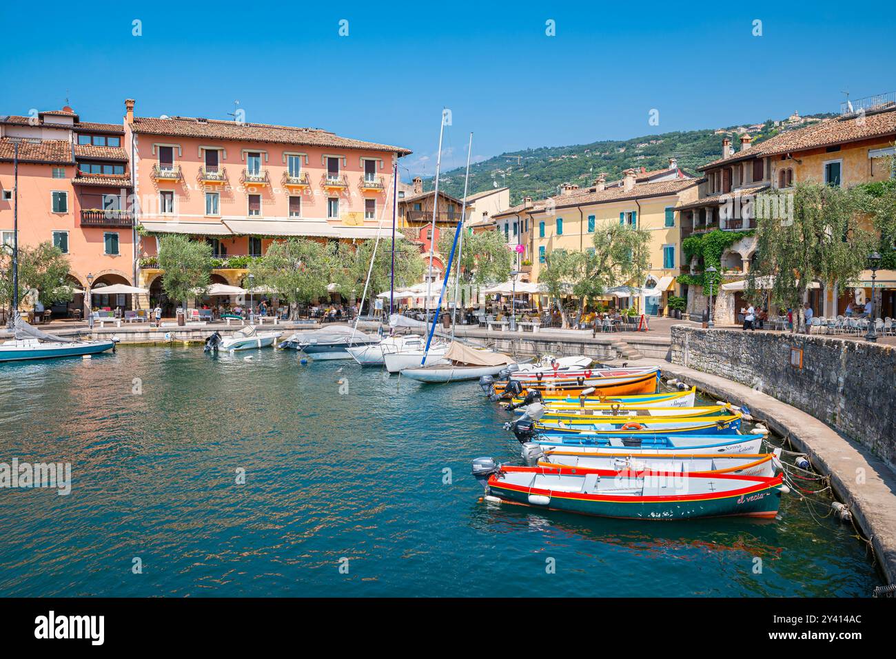 Splendida vista delle barche colorate nel porto di Torri del Benaco sulla riva del Lago di Garda, Italia Foto Stock
