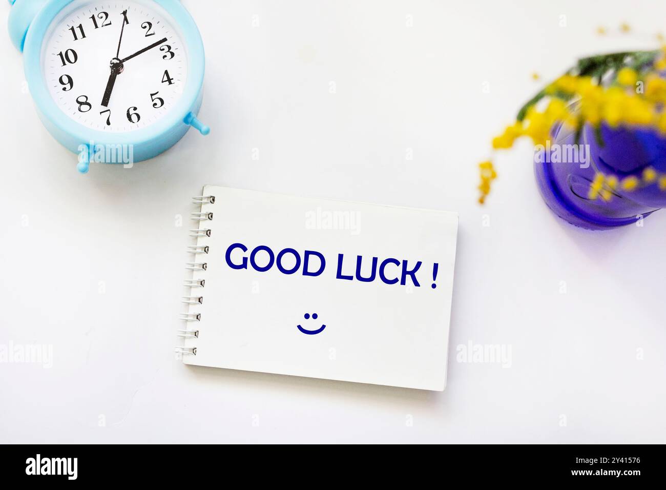 Simbolo di buona fortuna. Blocco note con le parole "buona fortuna". Sfondo bianco con piante e orologio. Business e buona fortuna. Copia spazio. Foto Stock