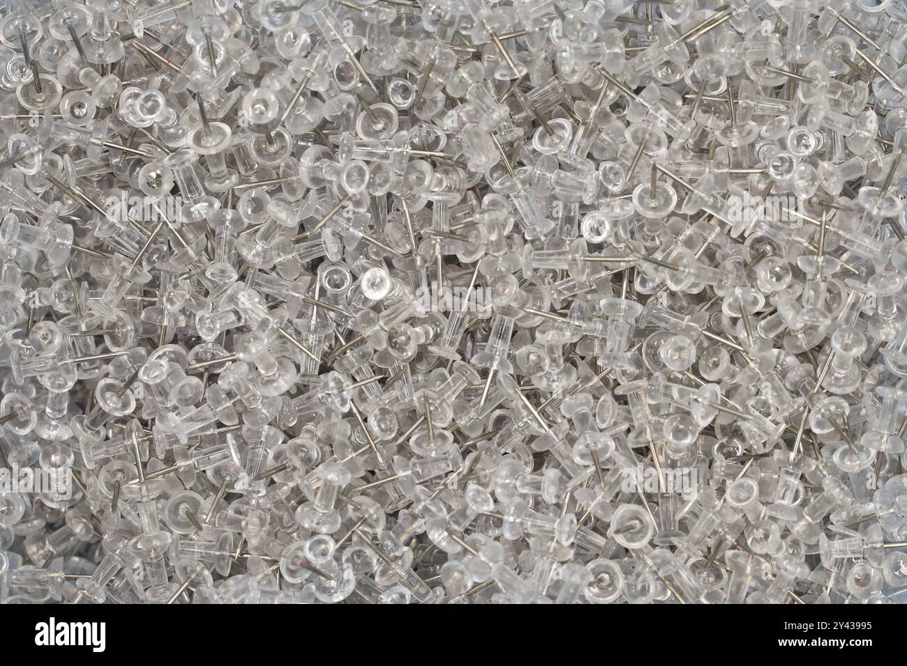 Un primo piano di migliaia di spille trasparenti da ufficio o da mestiere. Spilli per pollice o spilli a muro. Foto Stock