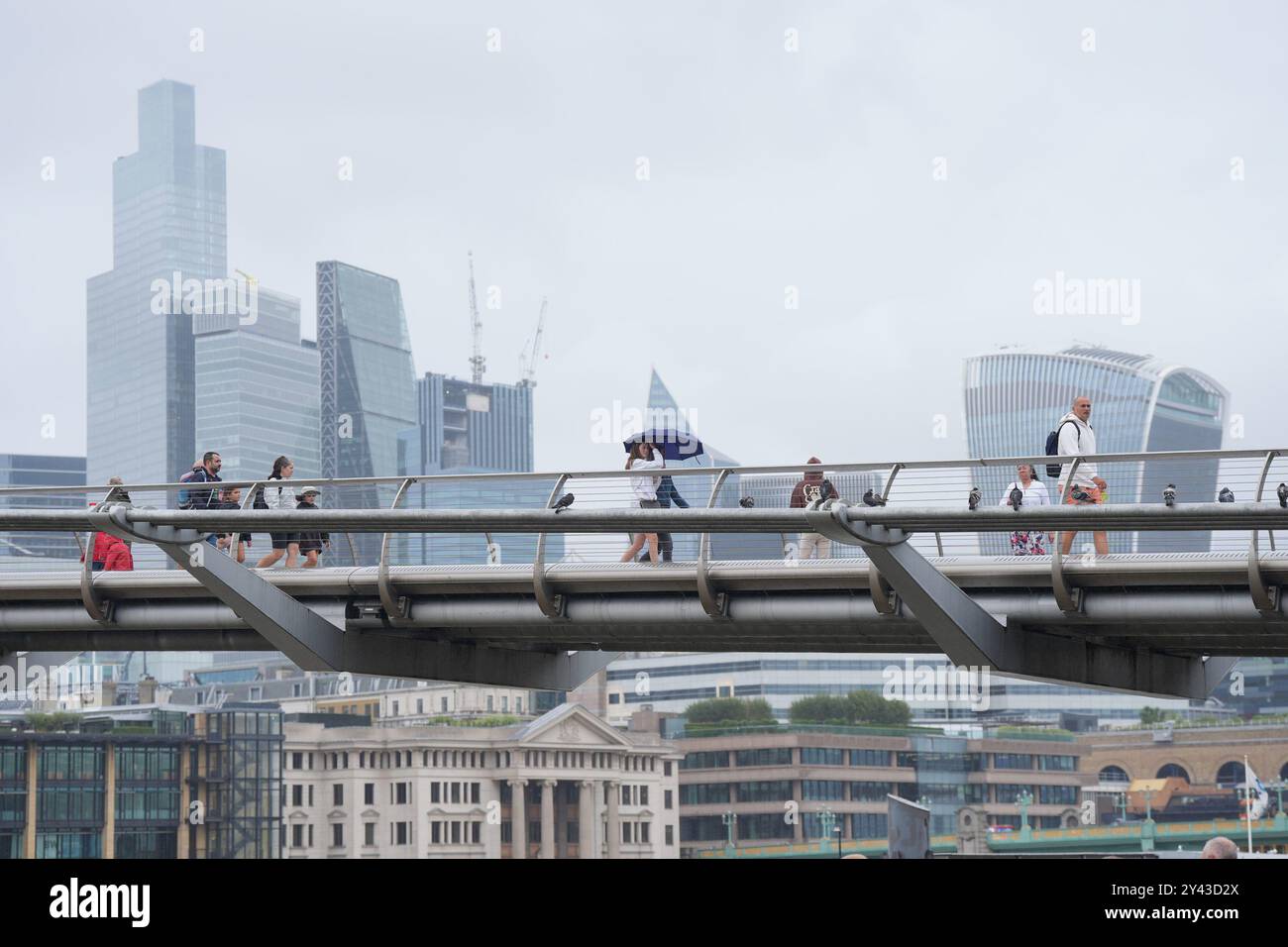 Foto del file datata 08/08/24, di persone che vengono catturate in una doccia a pioggia mentre attraversano il Millennium Bridge di Londra. Le imprese straniere stanno acquistando le quote più importanti nelle imprese britanniche, nonostante vi siano più accordi di private equity sul suolo britannico, nuovi dati mostrano. Circa 3,5 miliardi di sterline sono stati investiti in aziende in tutto il Regno Unito attraverso private equity tra maggio e luglio, secondo le analisi di Barclays e della società di dati Beauhurst. Questo è stato superiore di circa il 3% rispetto al precedente periodo di tre mesi. Data di pubblicazione: Lunedì 16 settembre 2024. Foto Stock