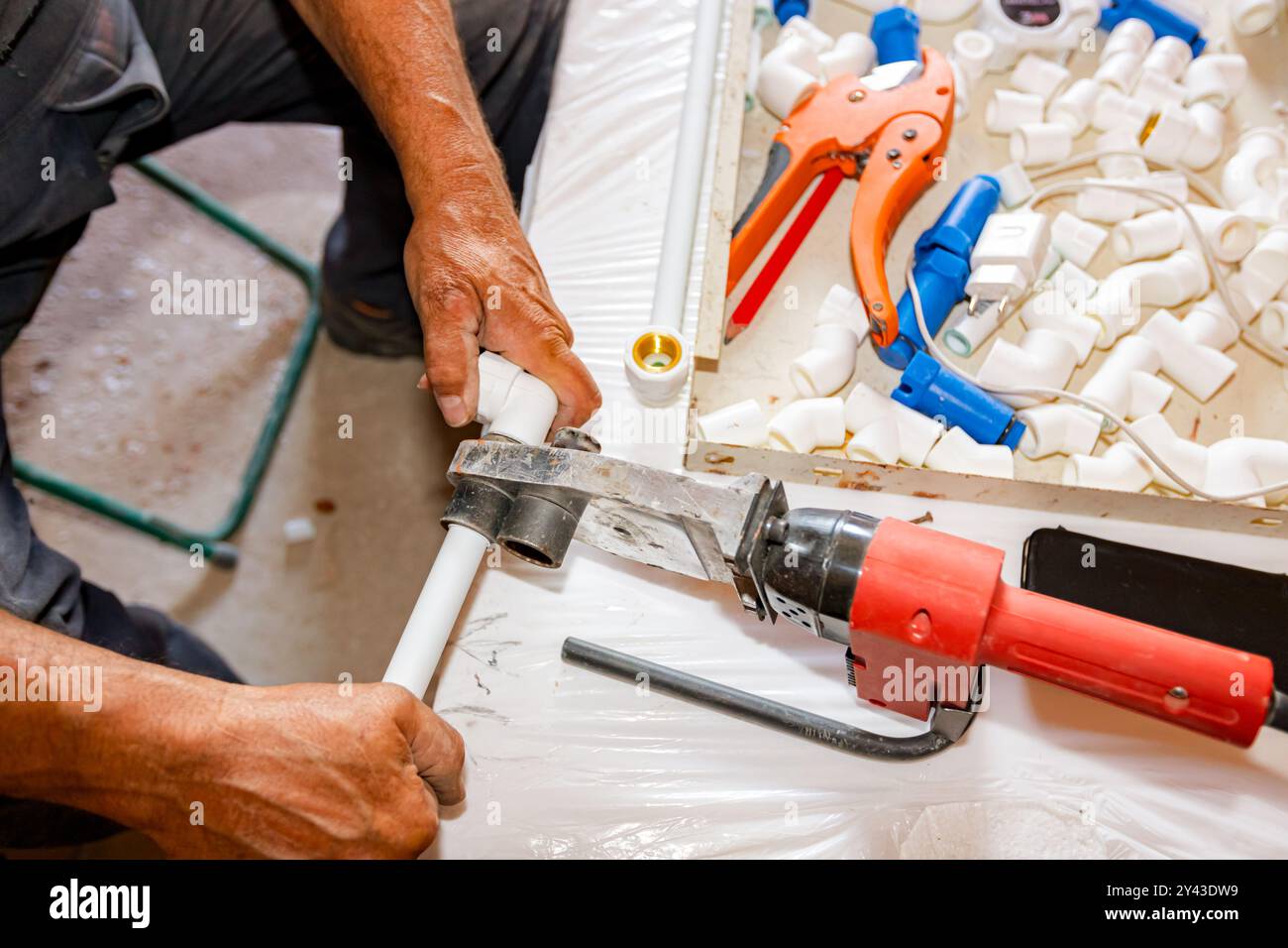 Le mani dell'idraulico come l'utilizzo di un pratico utensile elettrico, il ferro per la saldatura, la saldatura di tubi in polipropilene, il collegamento in tubazioni, l'officina in cantieri interni Foto Stock