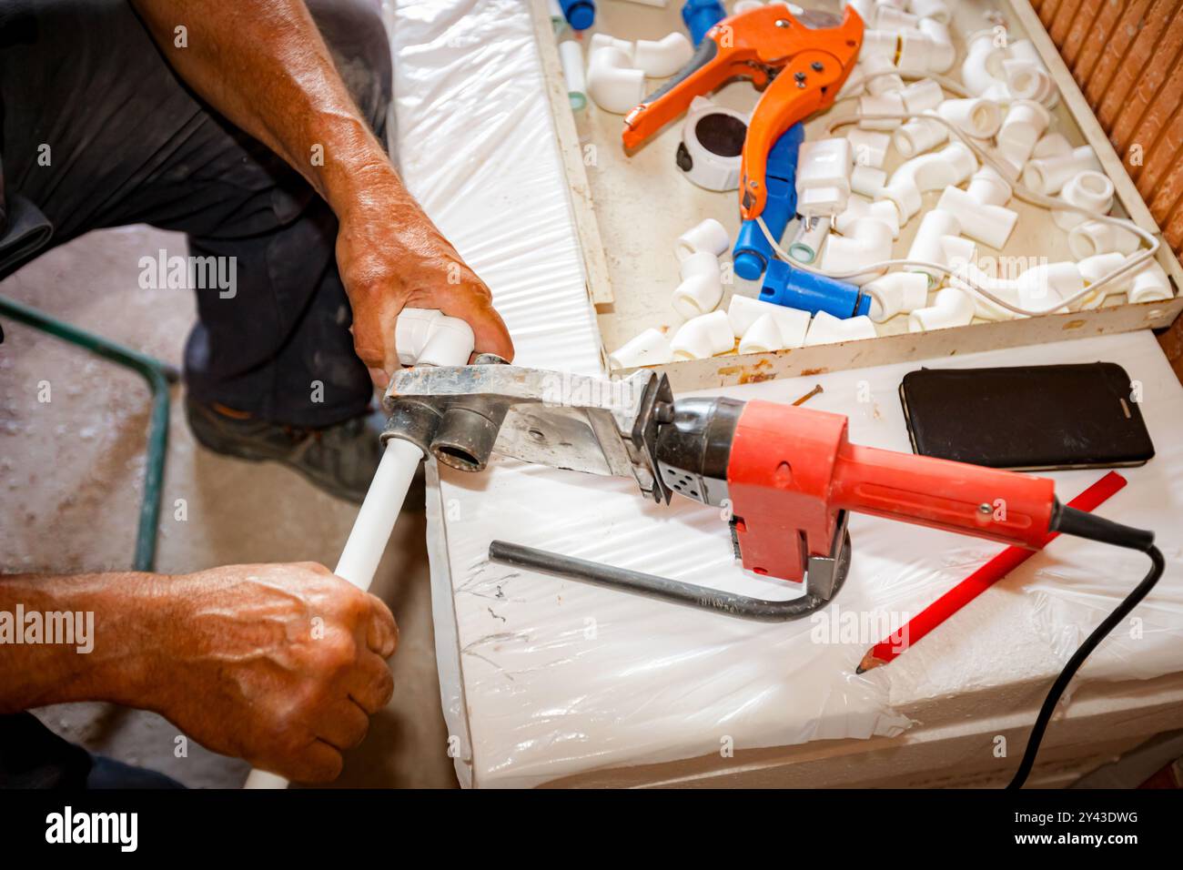Le mani dell'idraulico come l'utilizzo di un pratico utensile elettrico, il ferro per la saldatura, la saldatura di tubi in polipropilene, il collegamento in tubazioni, l'officina in cantieri interni Foto Stock