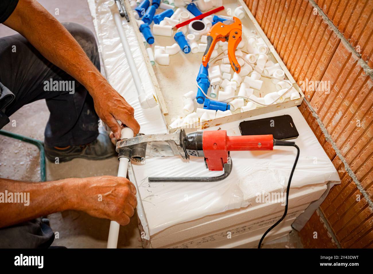 Le mani dell'idraulico come l'utilizzo di un pratico utensile elettrico, il ferro per la saldatura, la saldatura di tubi in polipropilene, il collegamento in tubazioni, l'officina in cantieri interni Foto Stock