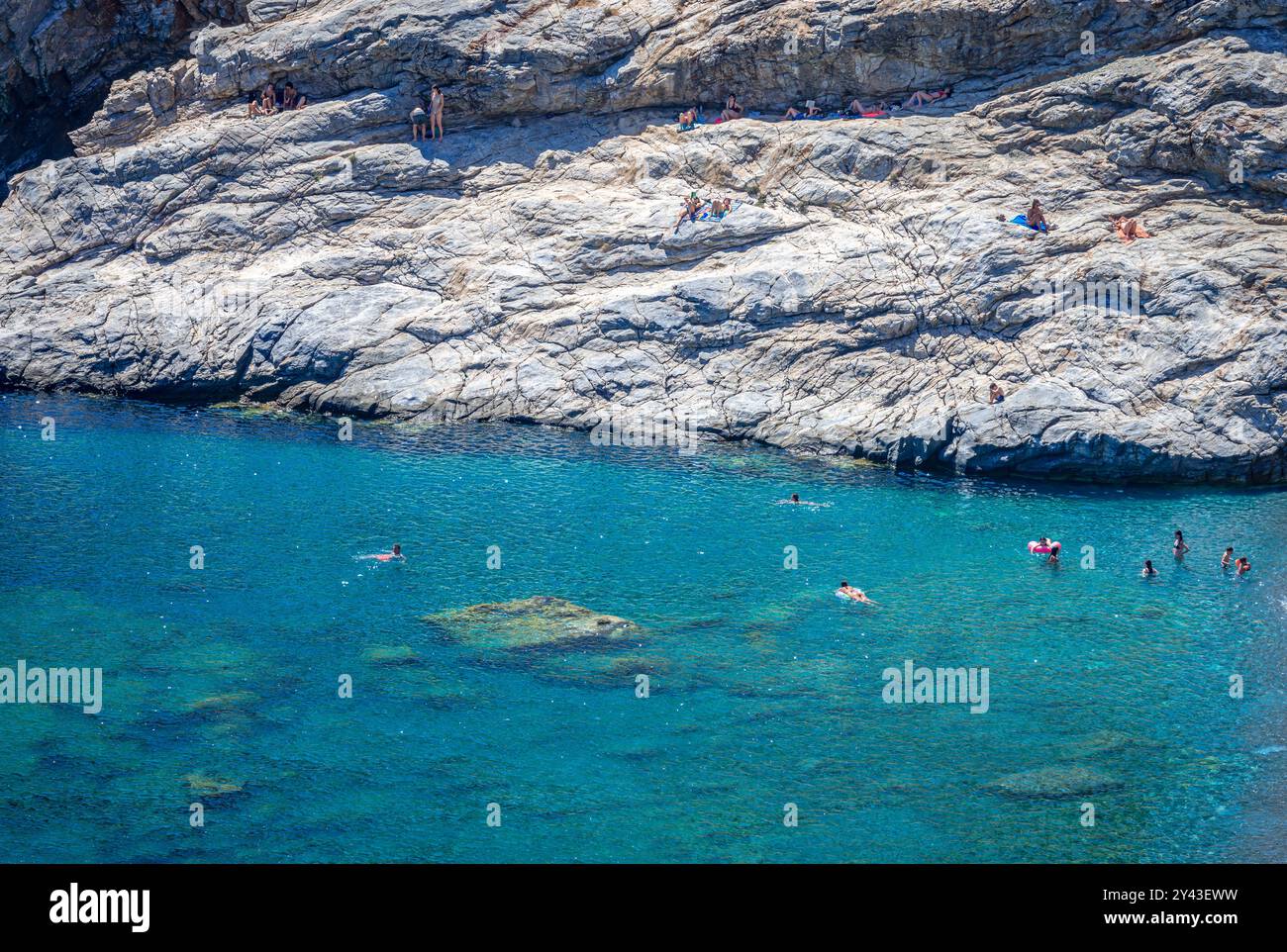 Nuotate in mare e sulle scogliere all'estremità della spiaggia di Mouros, un'incredibile spiaggia di ciottoli nell'isola di Amorgos, Cicladi, Grecia Foto Stock