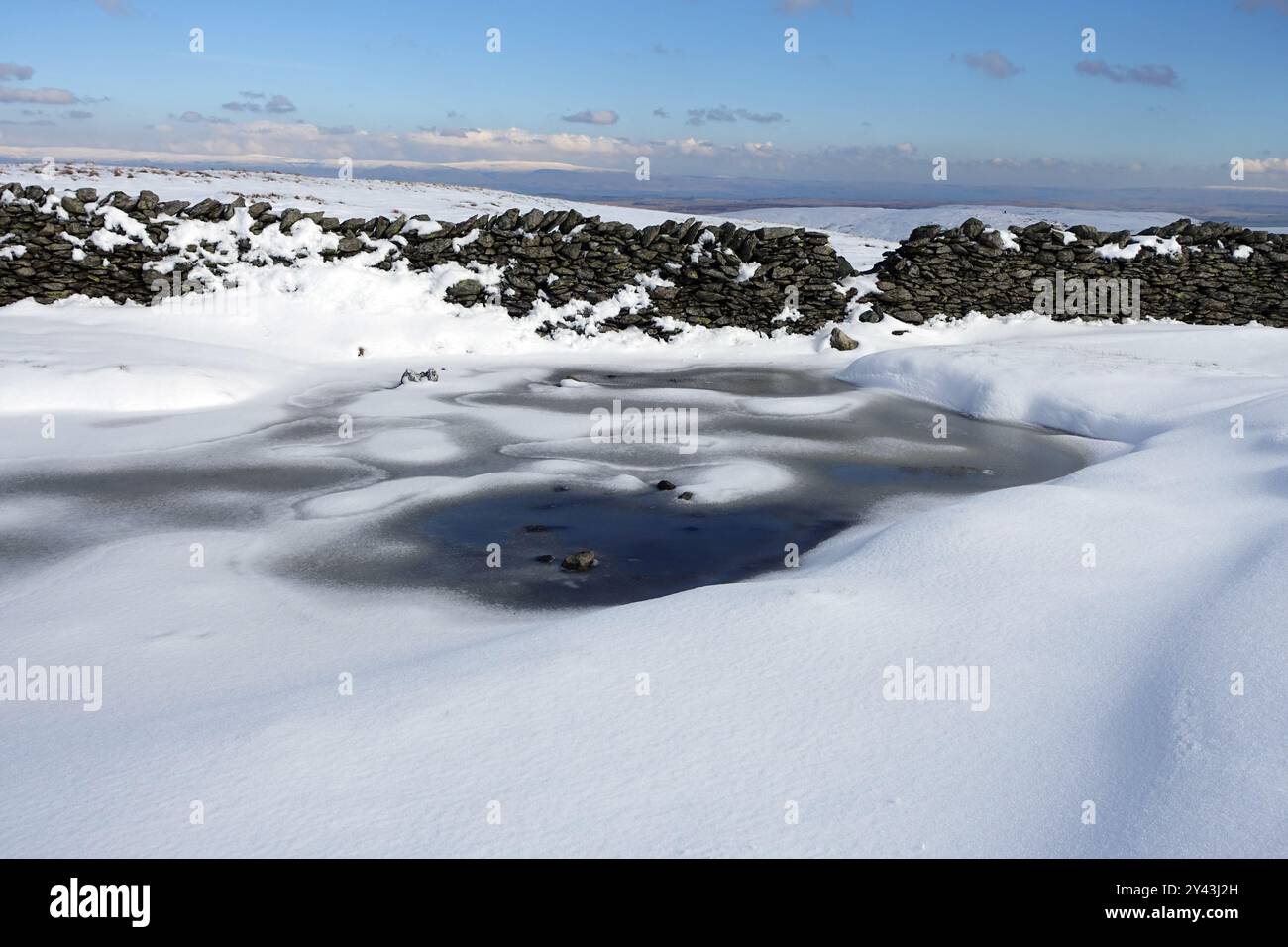 Dry Stone Wall, Deep Snow e un pozzanghere ghiacciato vicino alla vetta del Wainwright 'Kentmere Pike' nel Lake District National Park, Cumbria, Regno Unito Foto Stock