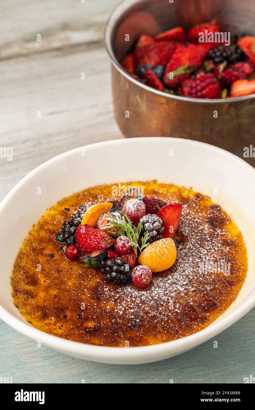 Crema brulee decorata con frutta e zucchero a velo su un tavolo di legno Foto Stock