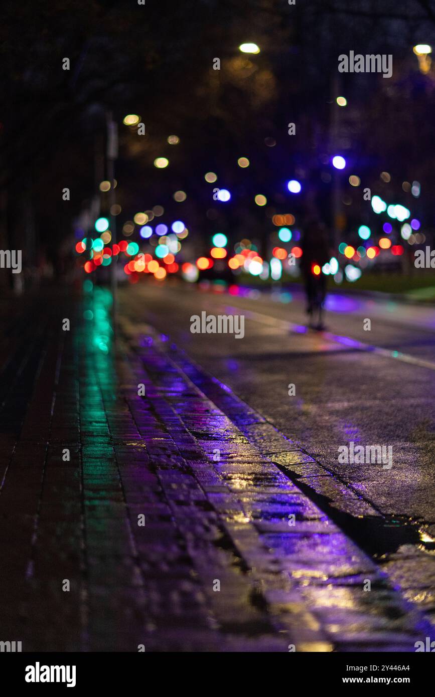 Strada cittadina bagnata con colorate luci bokeh di notte Foto Stock