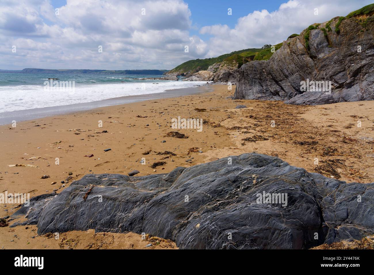Bassa marea su una spiaggia deserta di Hemmick in Cornovaglia in una nuvolosa giornata estiva. Foto Stock