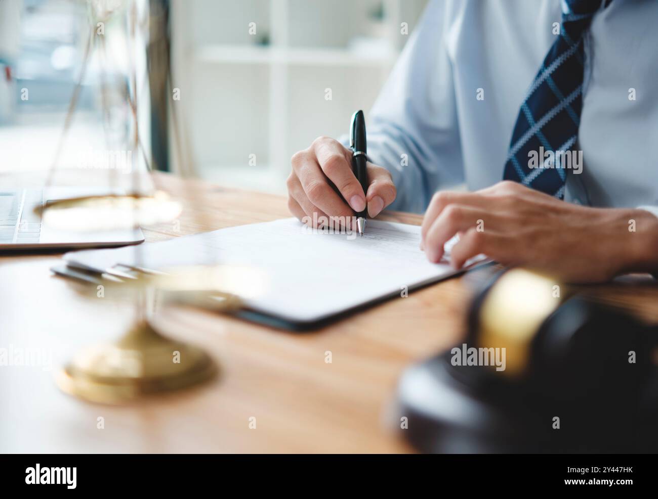 Un avvocato in causa è seduto alla sua scrivania, a firmare documenti legali Foto Stock