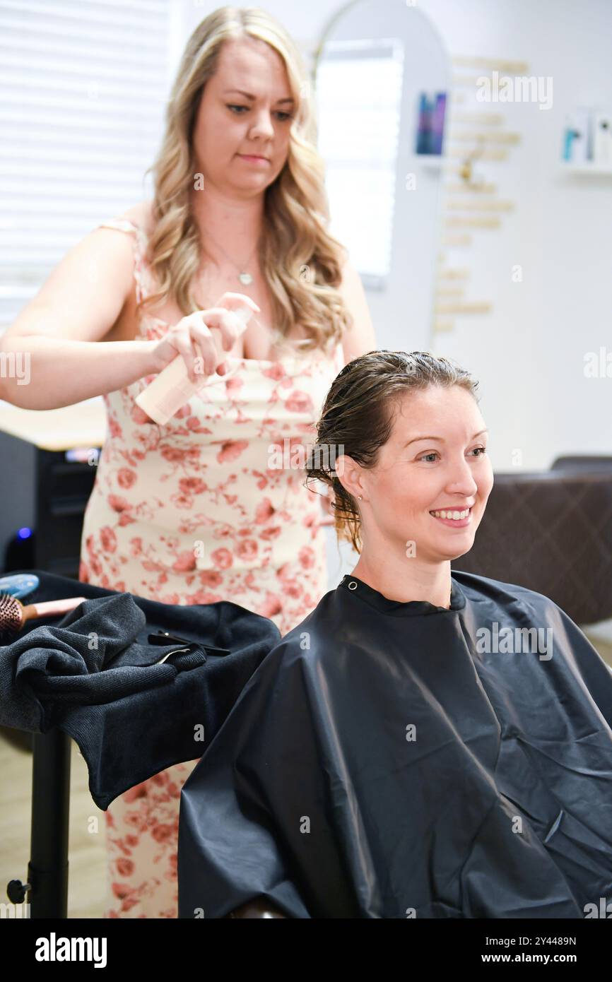 Parrucchiere applicazione di prodotti per capelli ai capelli umidi del cliente in una sal Foto Stock