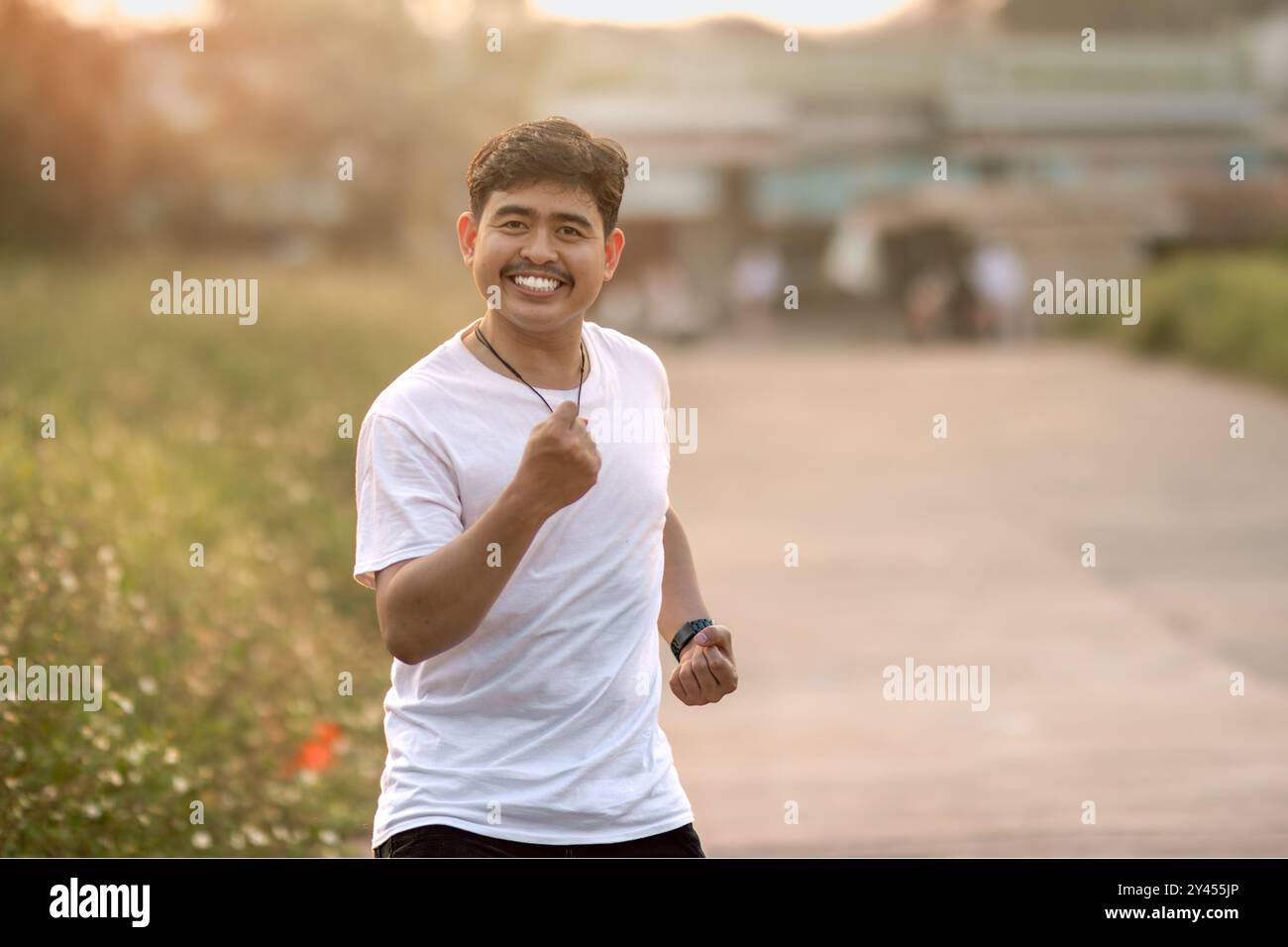 un uomo che stava in piedi e sorrideva goofily. L'uomo si comportava come se stesse correndo. immerso nella natura in un pomeriggio di sole. Foto Stock