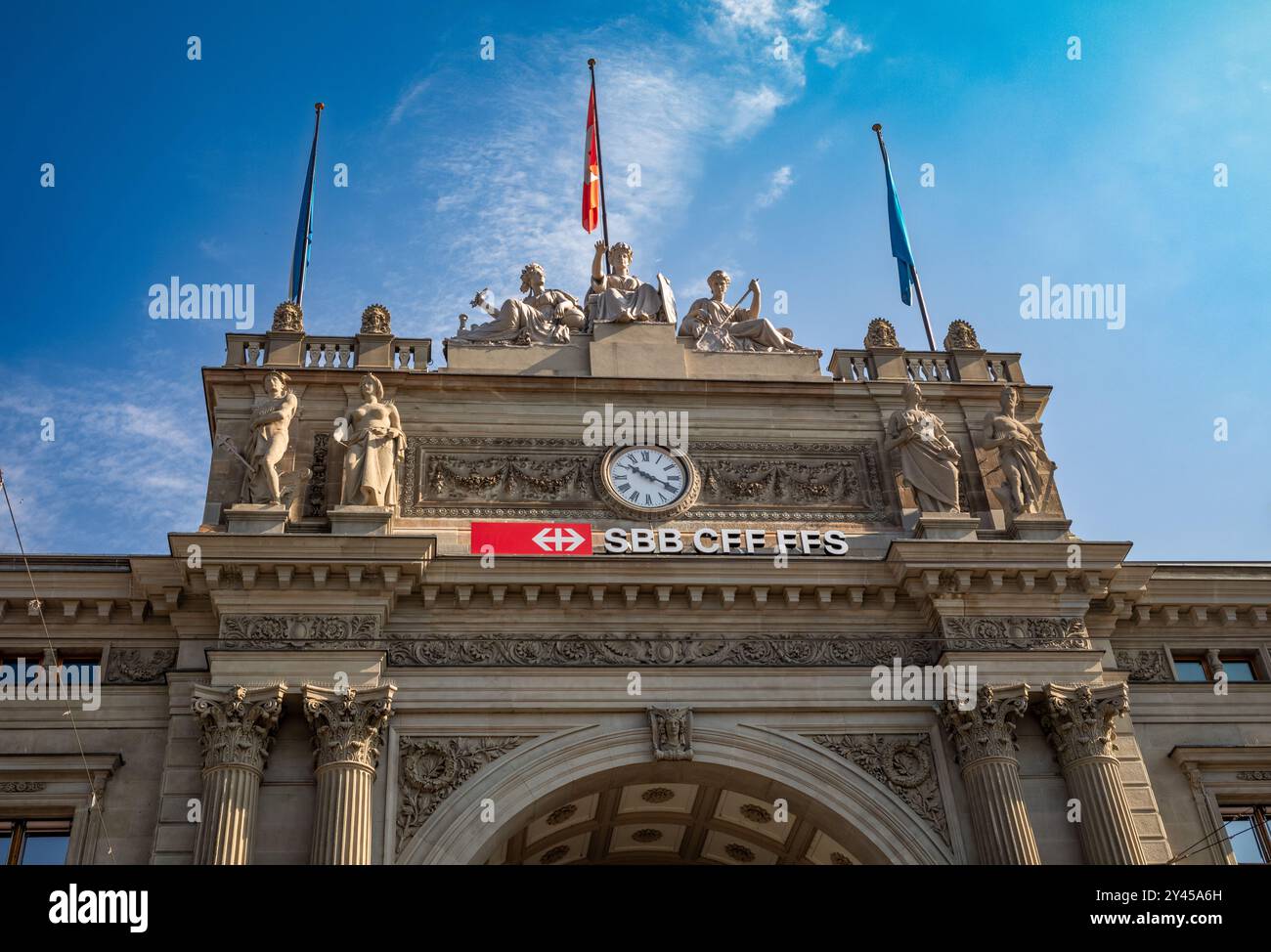 La storica facciata neorinascimentale di Zurigo HB, una delle stazioni ferroviarie più iconiche della Svizzera con il suo arco, le decorazioni in pietra e l'orologio. Foto Stock