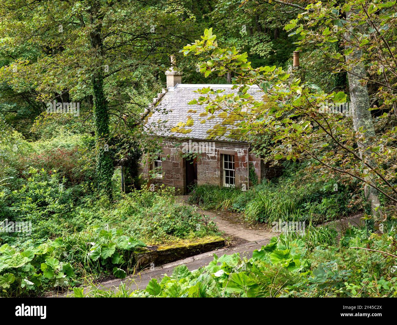 Il cottage del gestore della fabbrica di gas presso il Culzean Castle, una tradizionale casa isolata in pietra annidata nel verde lussureggiante bosco scozzese sulla costa dell'Ayrshire Foto Stock