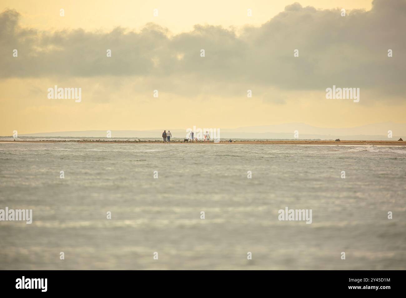 Vista lontana dello skyline di una famiglia che cammina insieme su una spiaggia di Barmouth, Gwynedd, Galles del Nord, Regno Unito. Foto Stock