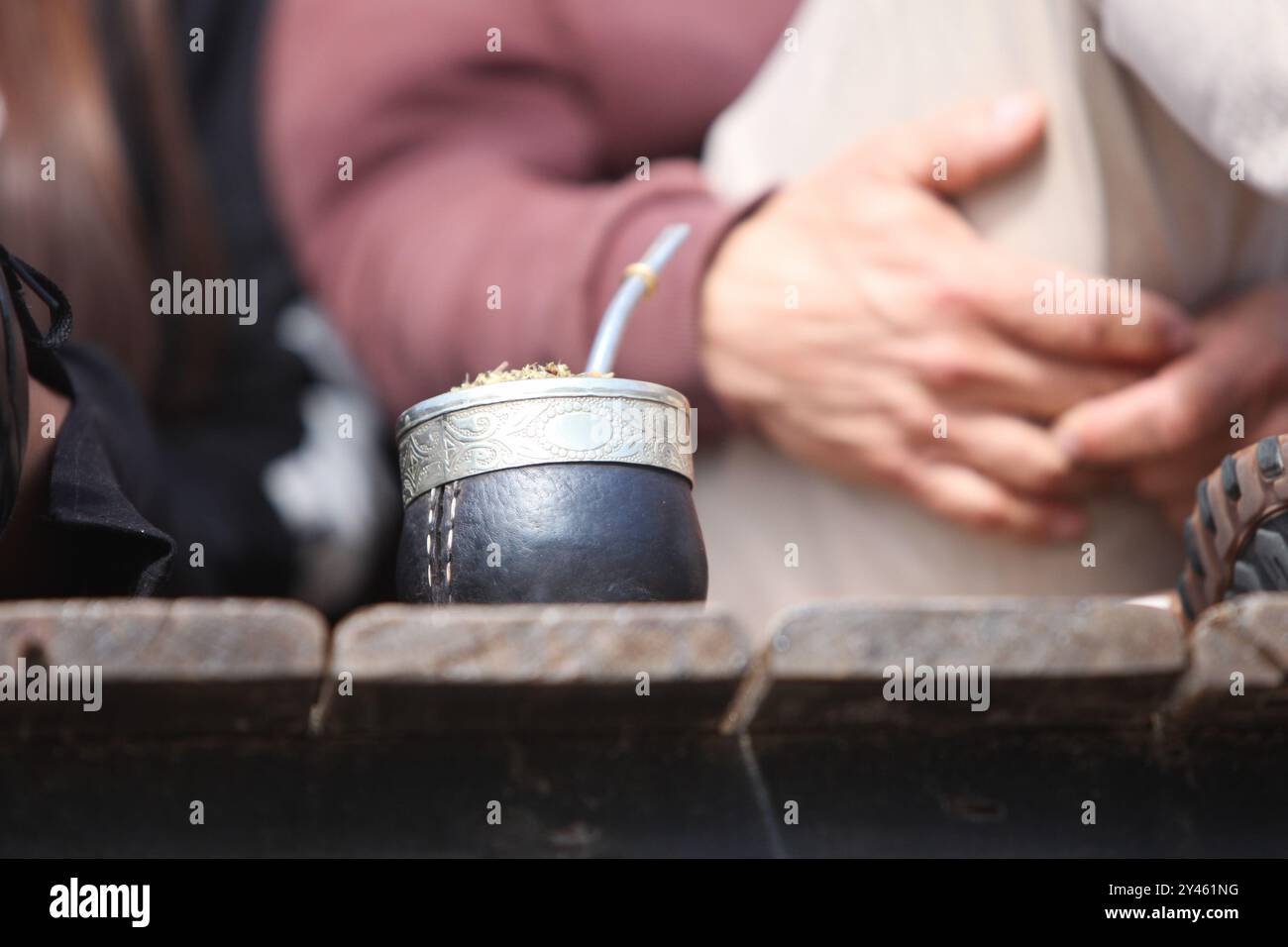 primo piano di Yerba Mate in piedi su un ponte di legno con persone irriconoscibili sullo sfondo Foto Stock