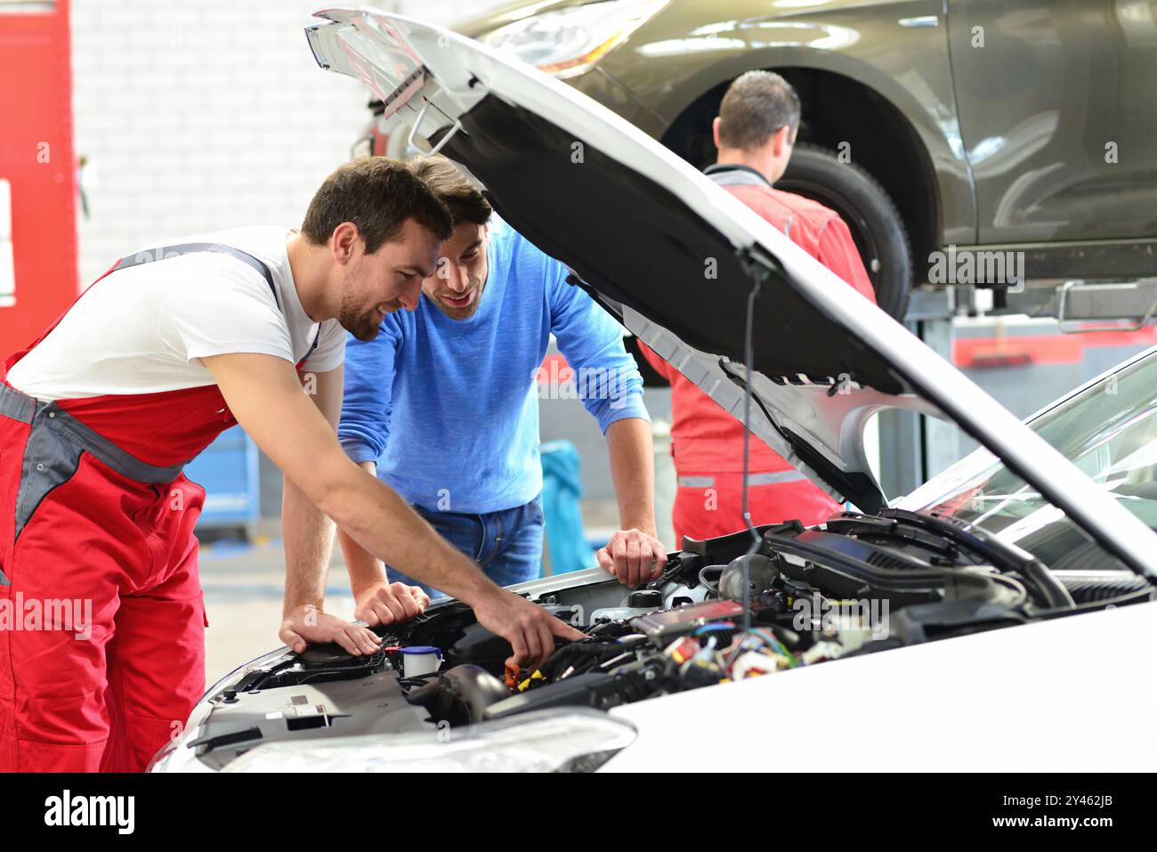 Servizio di assistenza post-vendita in riparazione auto shop - meccanico e l'uomo parla di riparazione di un veicolo Foto Stock