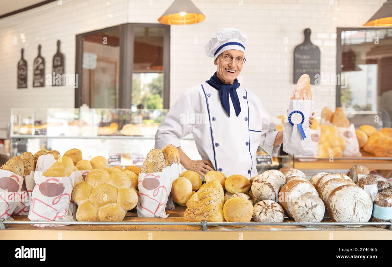Panettiere che tiene una pagnotta di pane con un ottimo premio all'interno di una panetteria Foto Stock