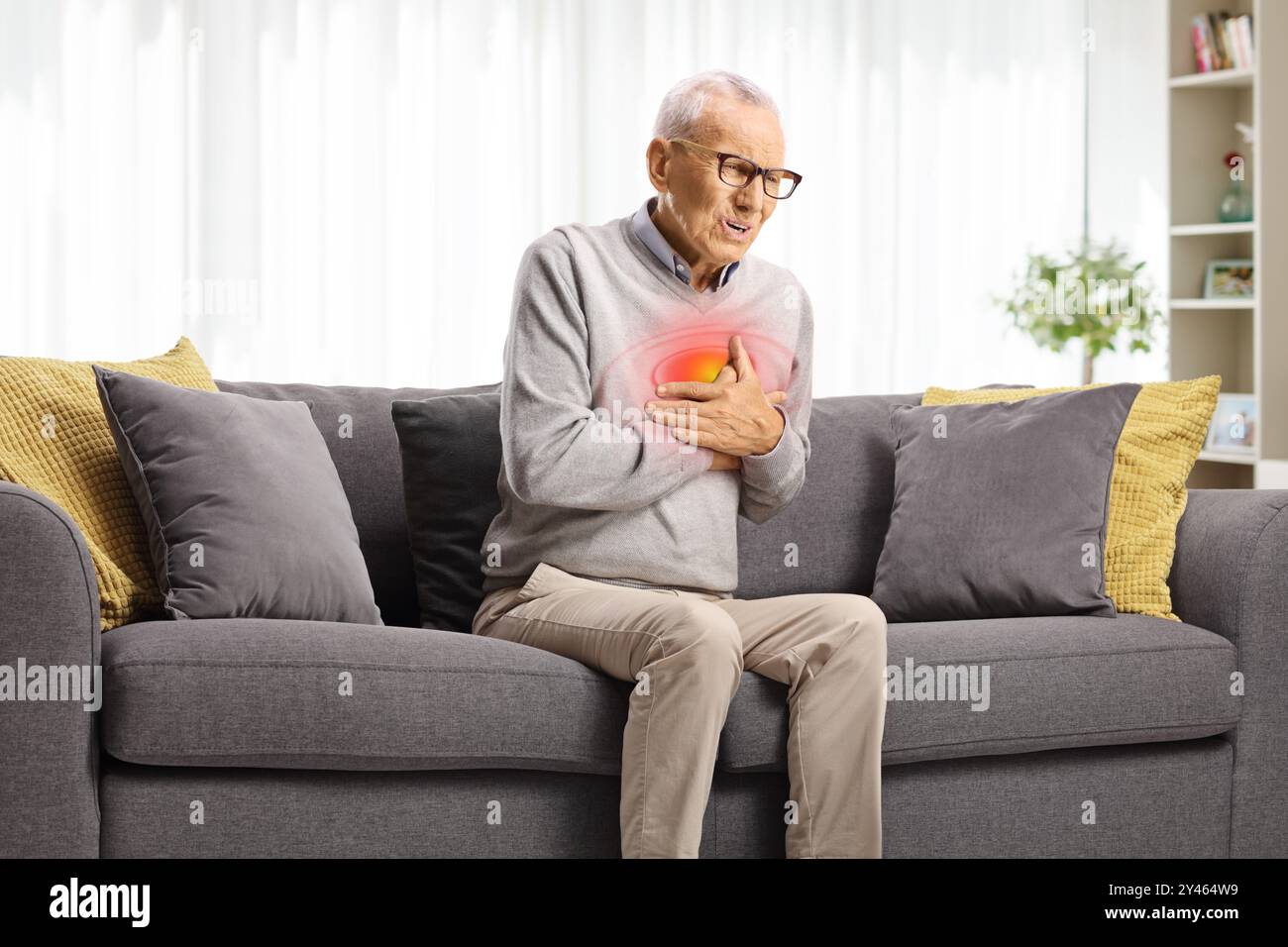 Uomo anziano con arresto cardiaco seduto su un divano in soggiorno Foto Stock
