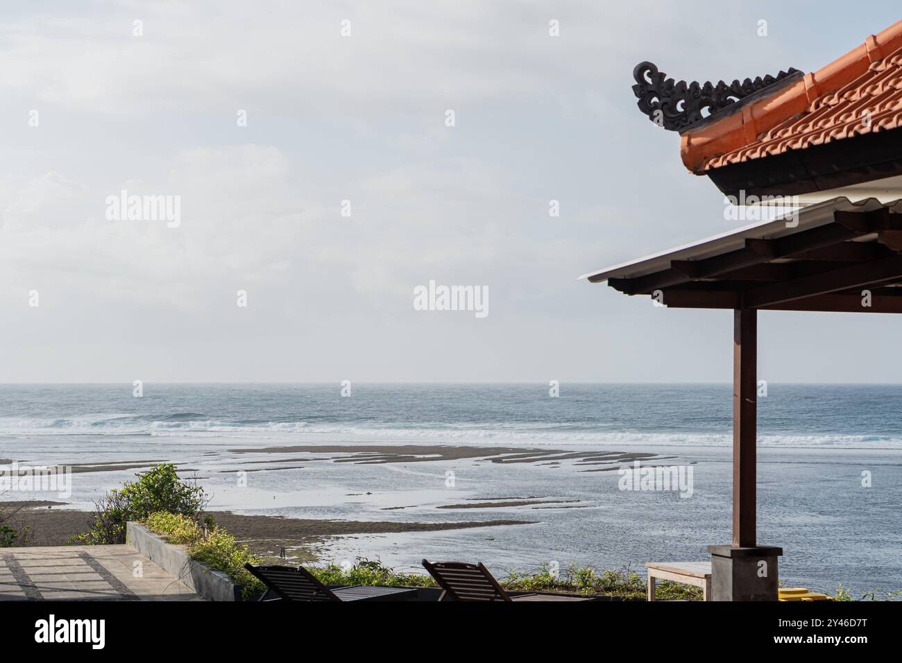 Una tranquilla vista sulla spiaggia con due sedie a sdraio affacciate sull'oceano. La scena include un cielo limpido con morbide nuvole, dolci onde che lambiscono sulla riva, Foto Stock