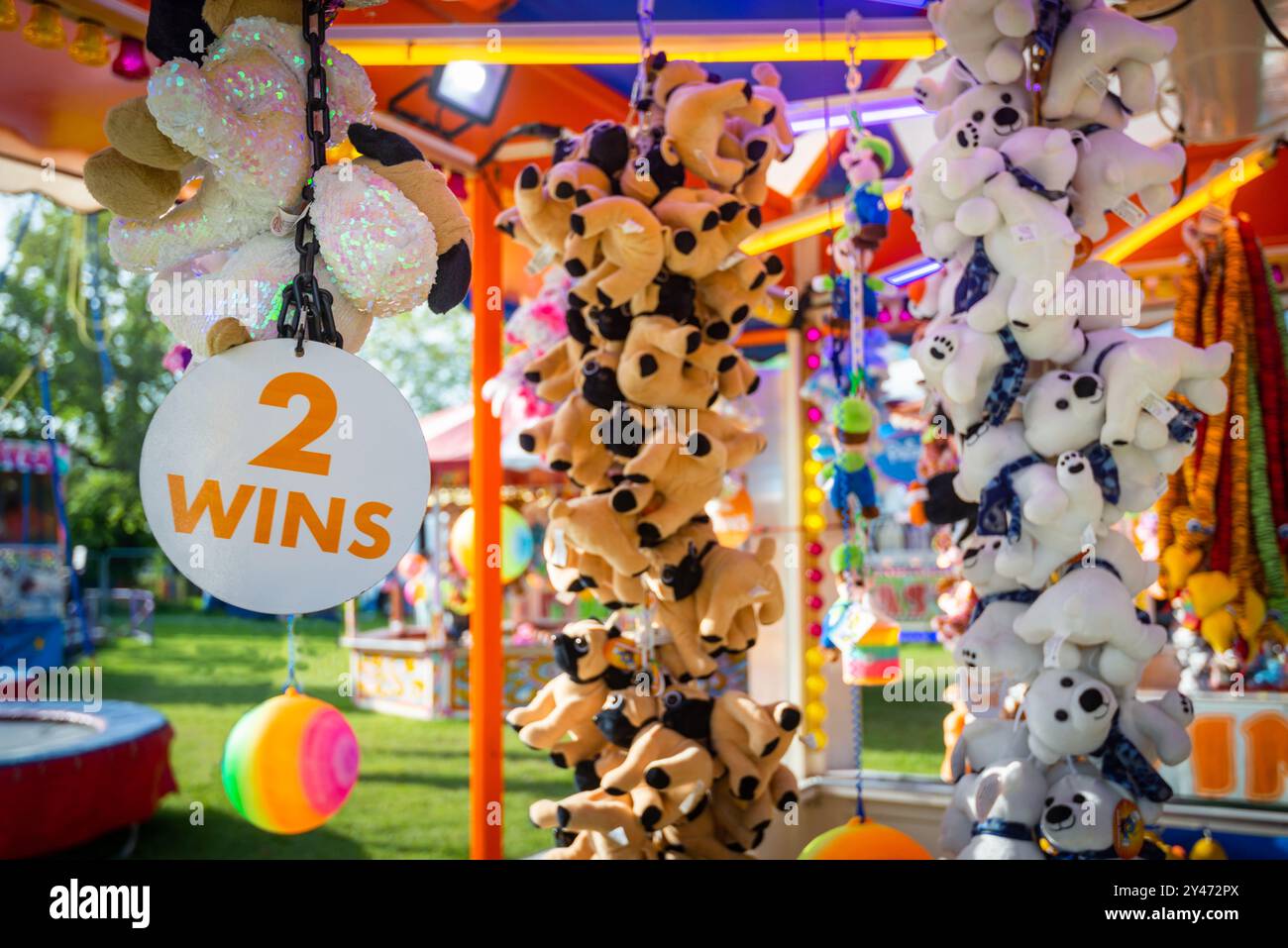 Simpatici premi di peluche appesi alla fiera del divertimento. Il cartello dice che 2 vince. Foto Stock