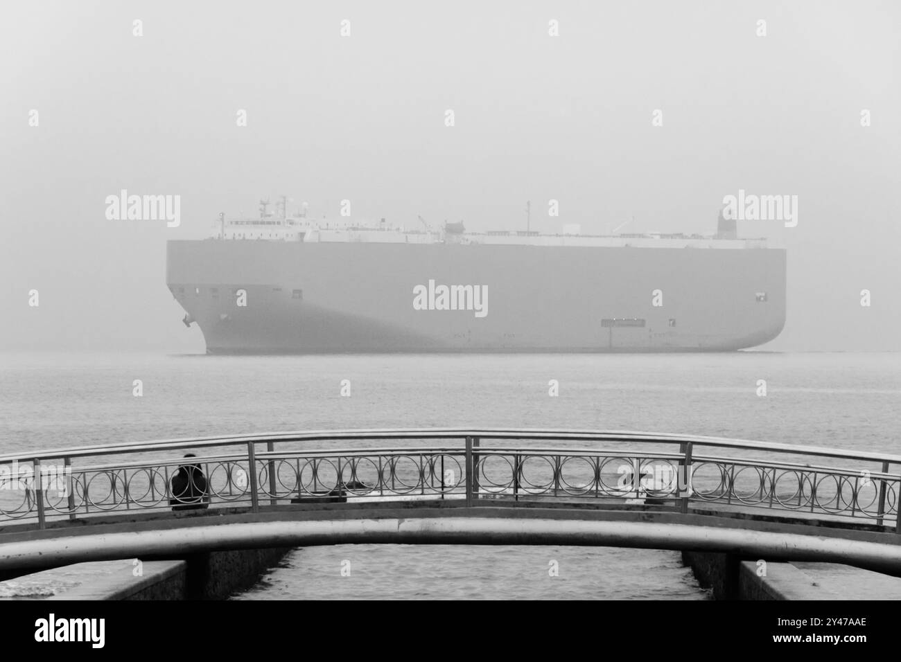 Città di Santos, Brasile. Roll and Roll Off nave che trasporta veicoli che passano all'orizzonte di fronte al ponte n. 6 del canale d'acqua in una giornata nebbiosa. Foto Stock