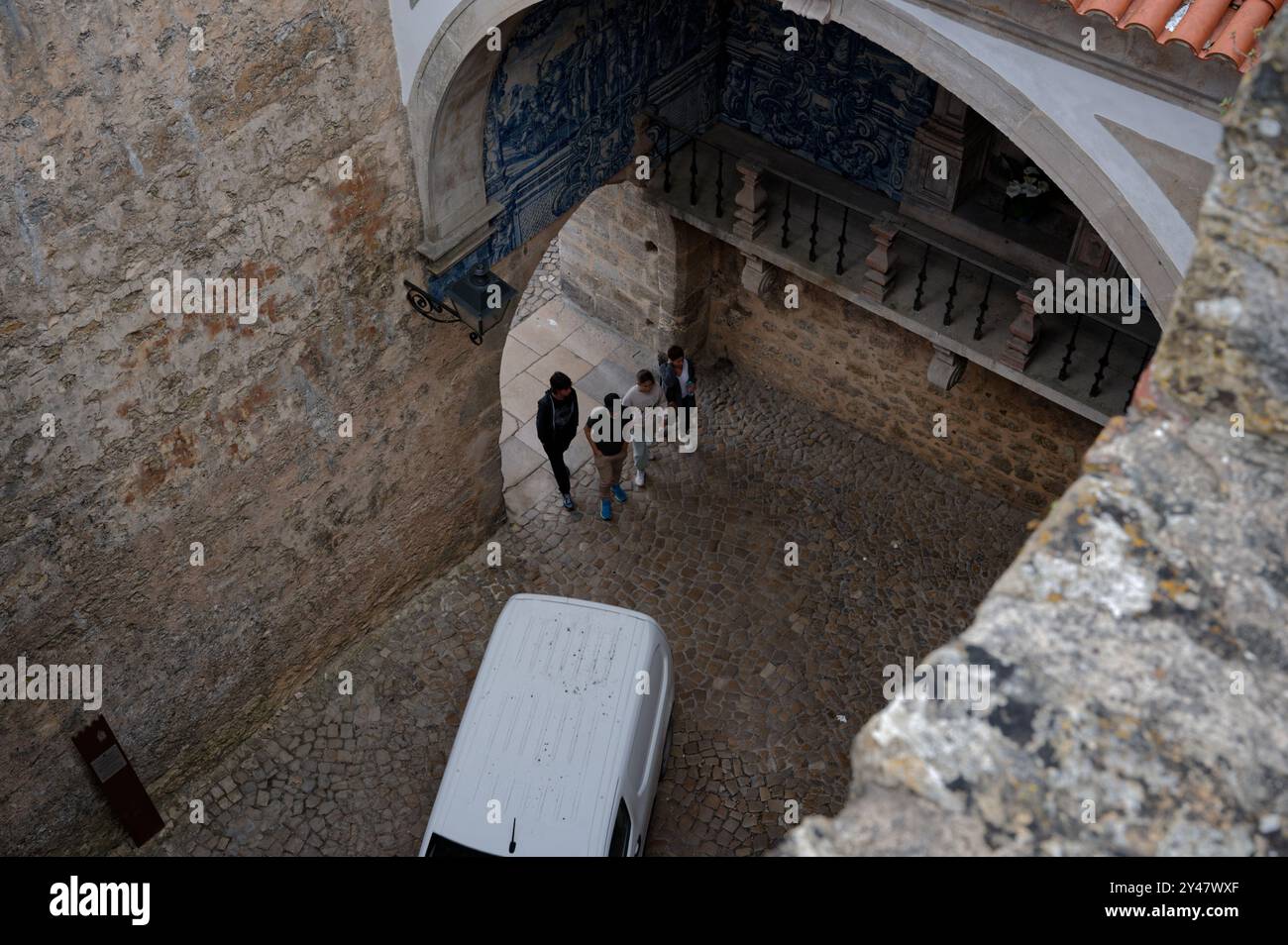 I visitatori camminano attraverso un arco di ciottoli, circondato da mura di pietra Foto Stock