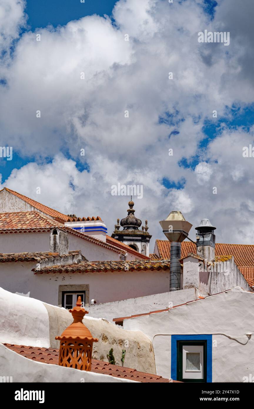 Tetti di tradizionali piastrelle di terracotta e dettagli ornati sotto le nuvole drammatiche a Óbidos Foto Stock