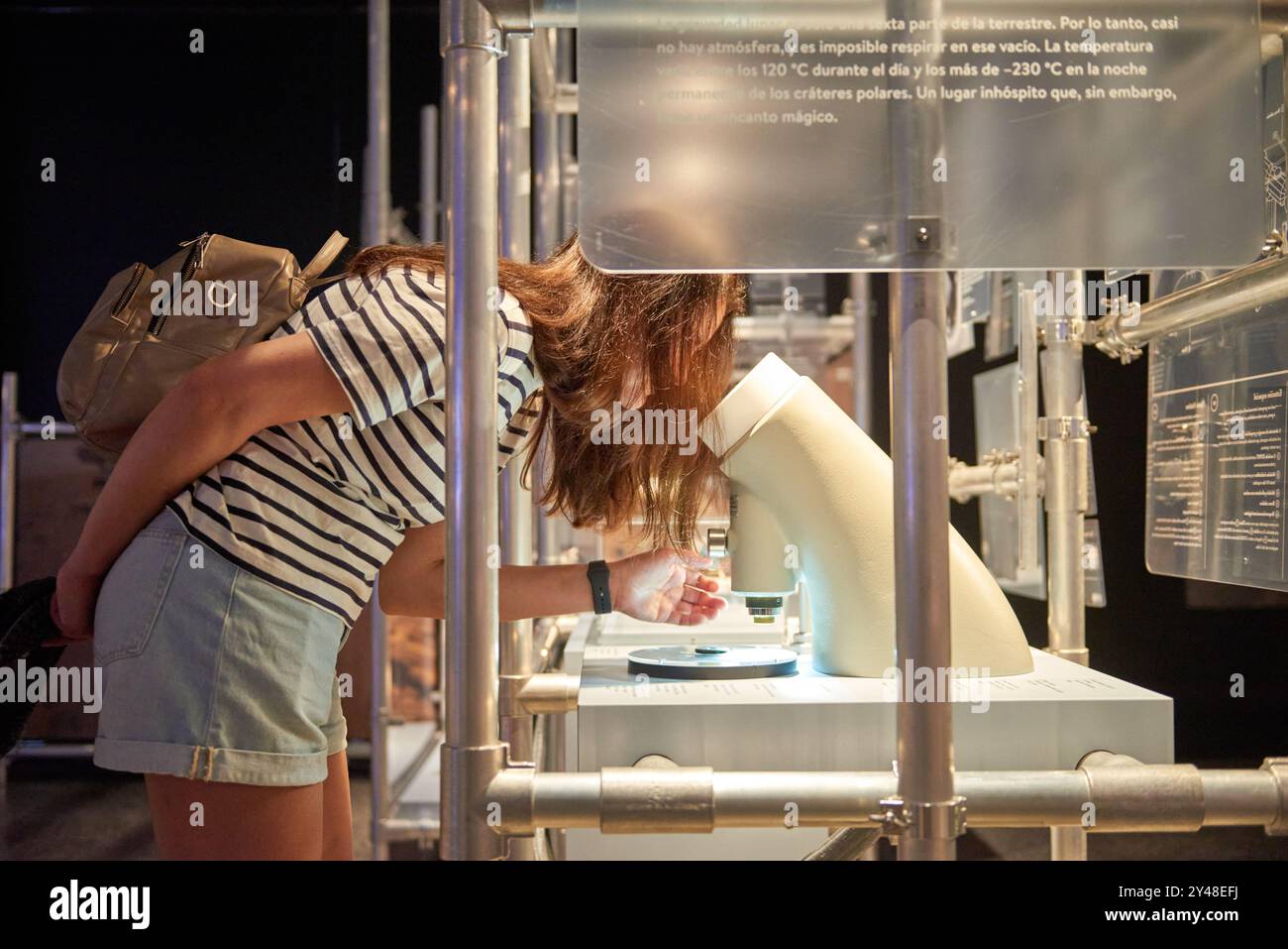 Young Scientist in Action: Girl Enrossed in Microscope Exploration presso la mostra scientifica del Museo interattivo. Avventura educativa: Enthusiastic Girl di Foto Stock