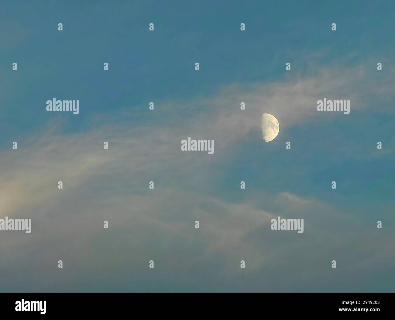 Fase Half Moon: Satellite della Terra contro un cielo blu nuvoloso Foto Stock