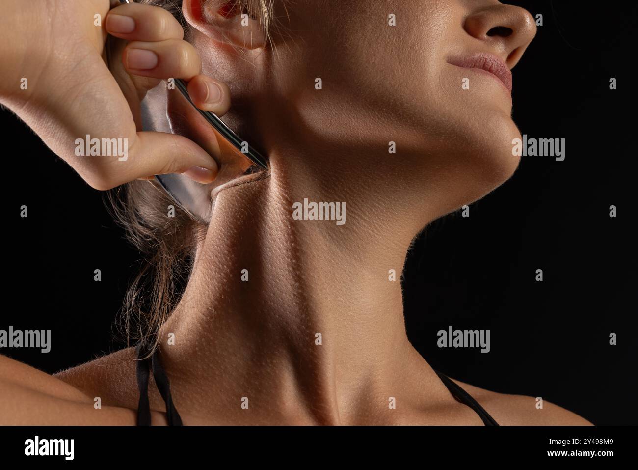 Donna utilizza uno strumento metallico per massaggi e mobilizzazione dei tessuti molli, strumenti IASTM intelligenti in acciaio inox per massaggi dei tessuti molli e sollievo dal dolore, Foto Stock